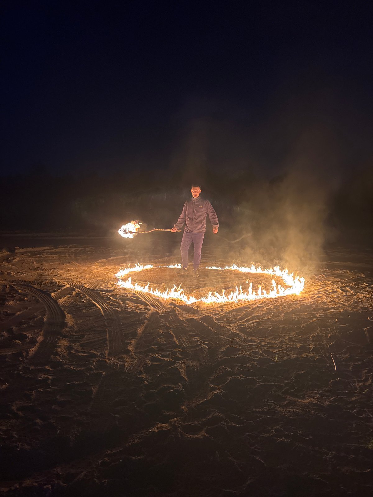 Man conducts nighttime fire ceremony on Russian beach