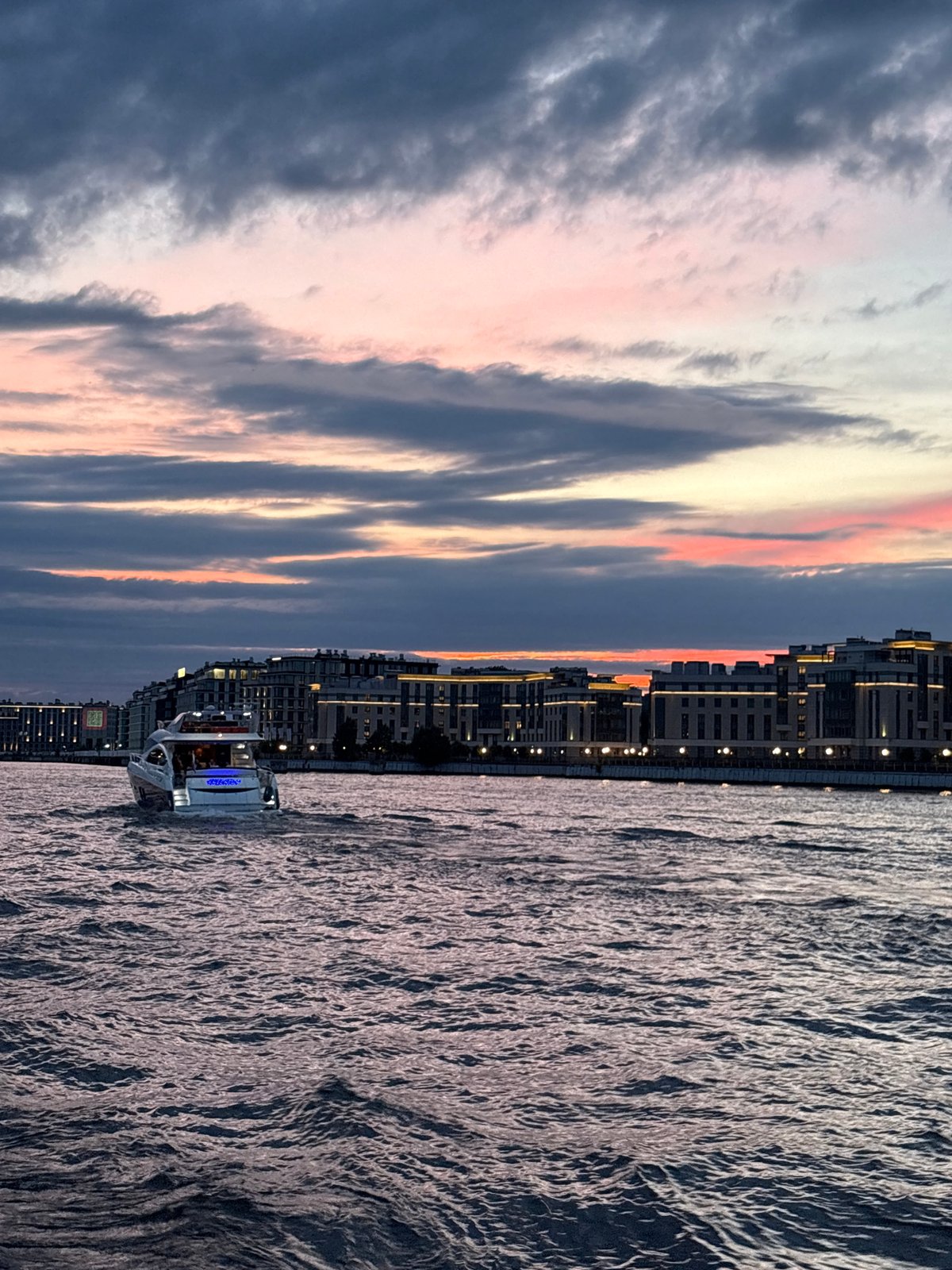 Evening boat party drifting past Saint Petersburg's lit waterfront