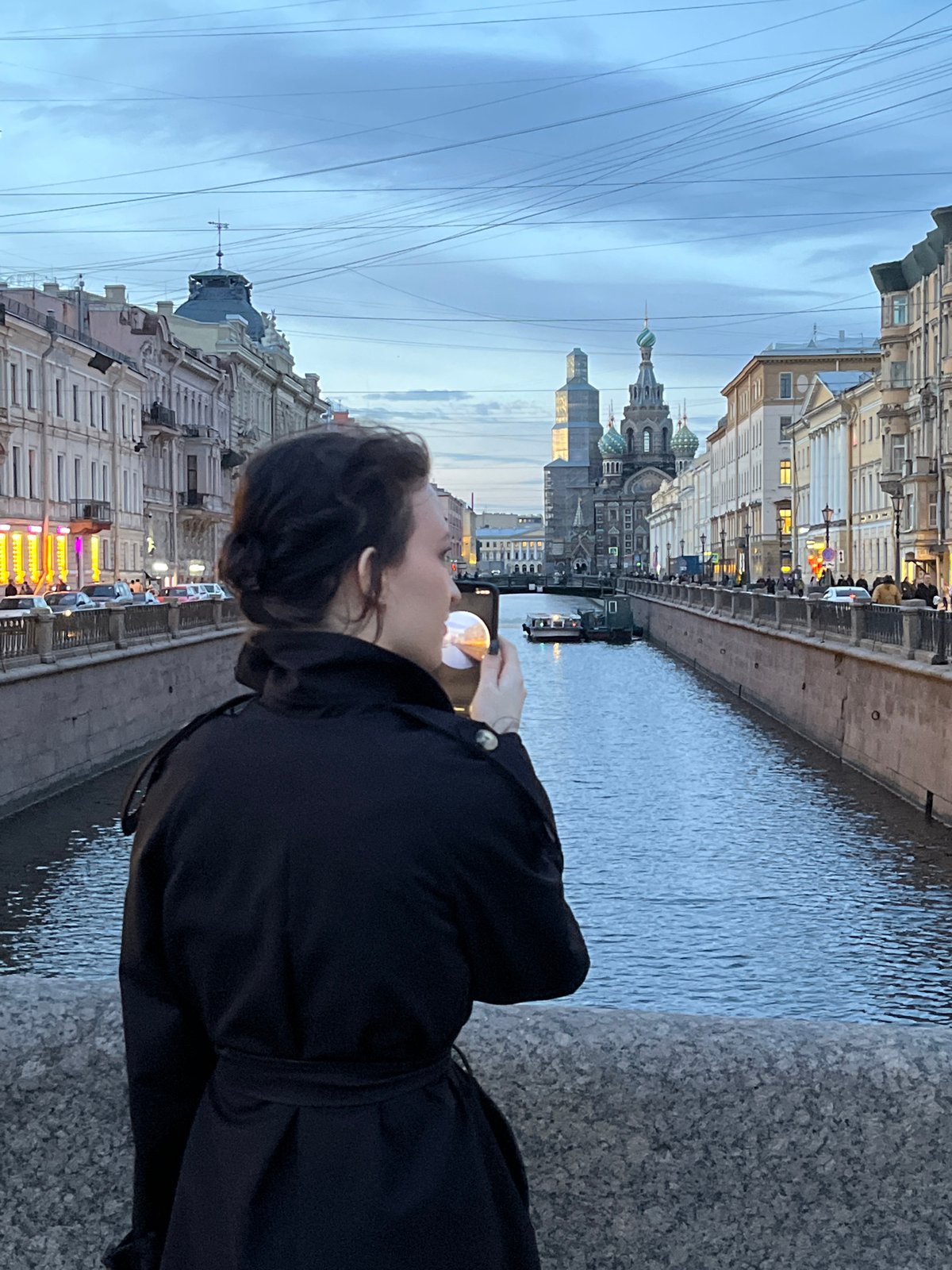 Woman photographs Saint Petersburg canal from granite bridge