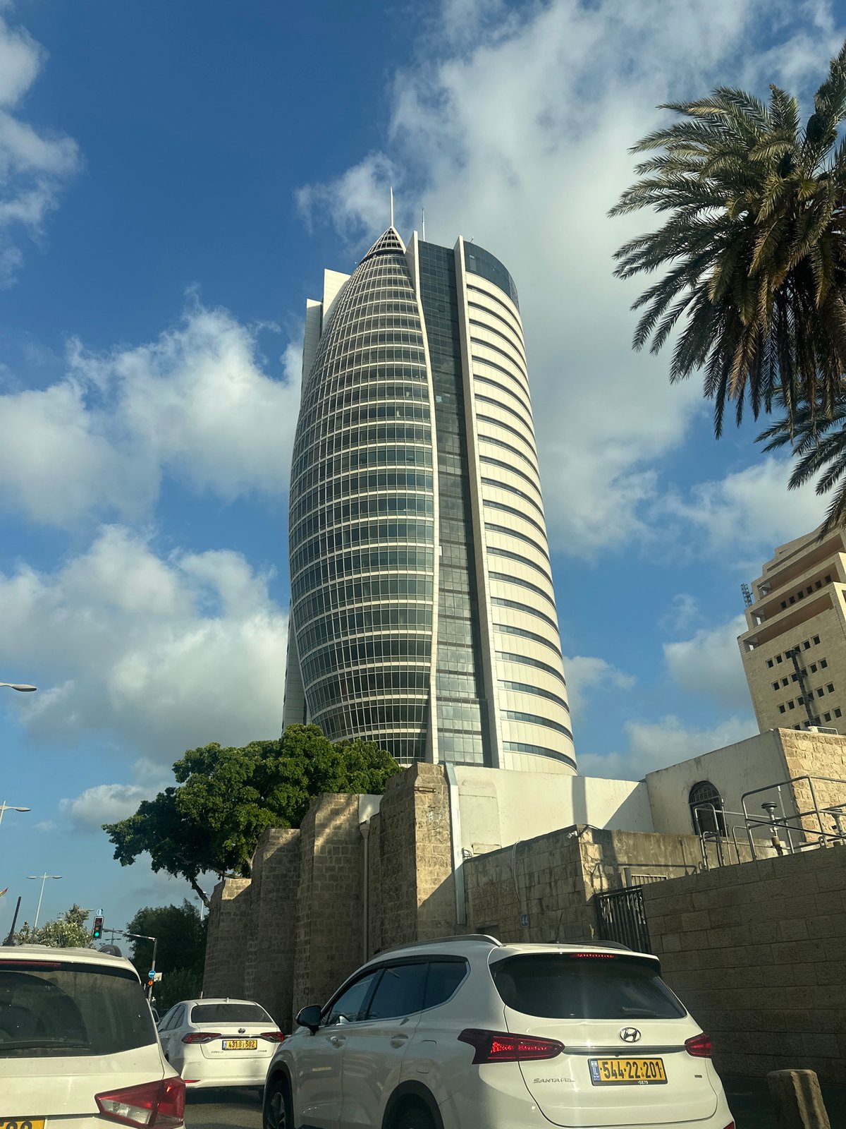 Haifa streets: glass tower, palm-lined boulevard, rainbow flag