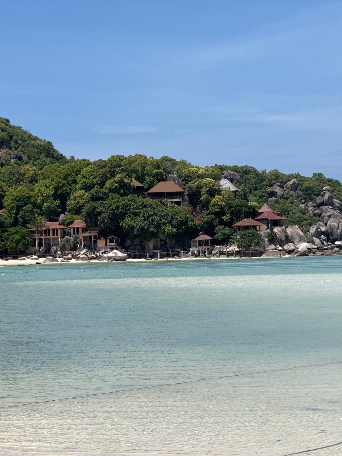 Clear water, sandy shore, and longtail boats at a tropical beach