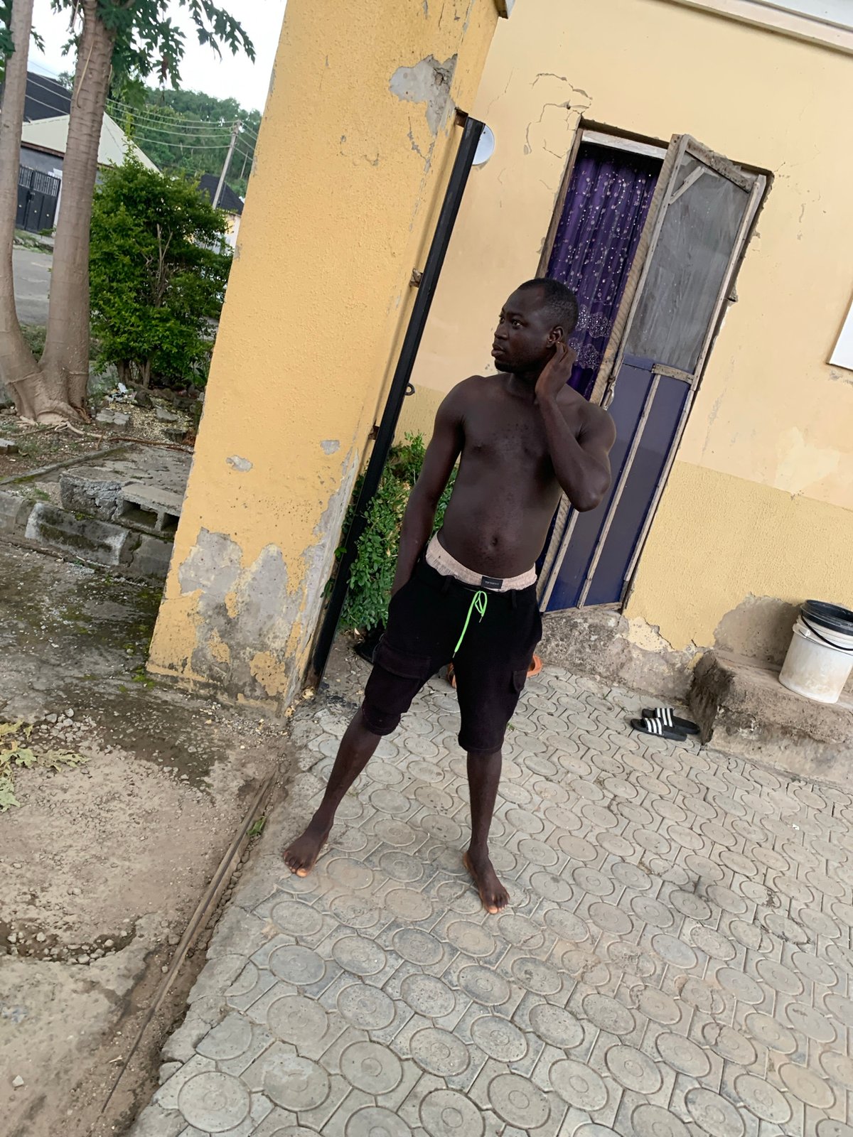 Casual afternoon activity outside a yellow building in Abuja