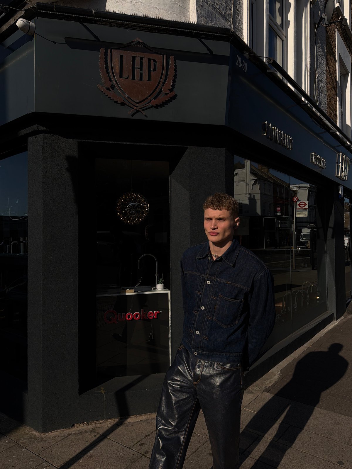 Young man photographed on London sidewalk outside modern shopfront