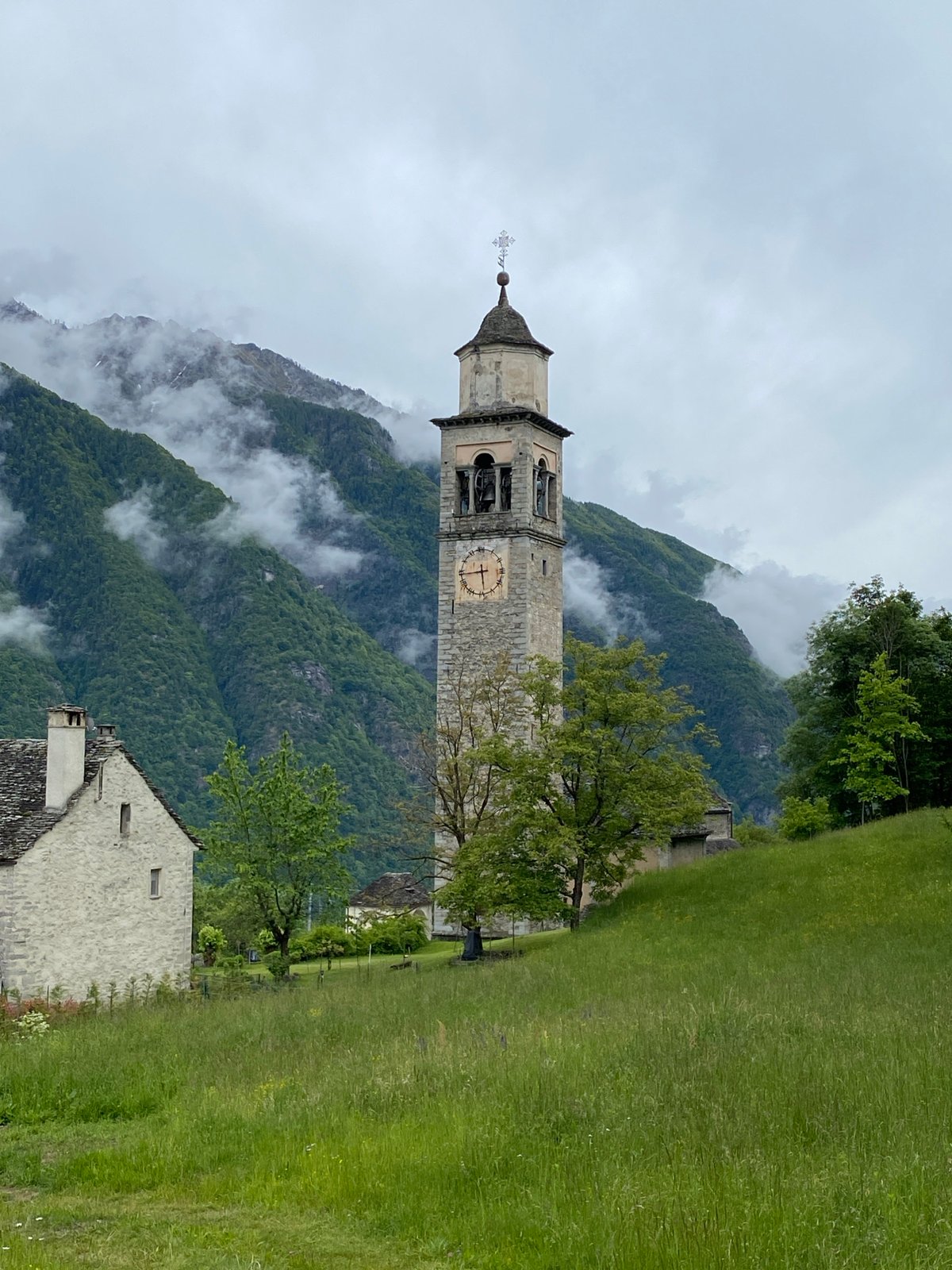 Church tower observed amid foggy mountains in Crodo, Italy