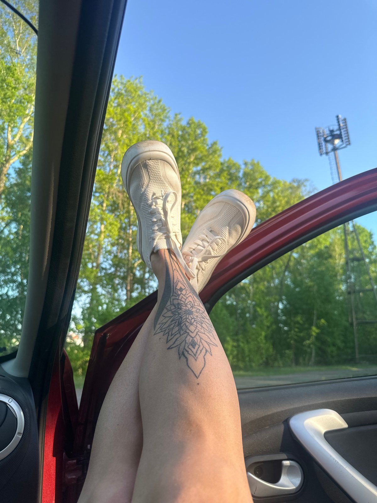Person sits in red car with legs out door