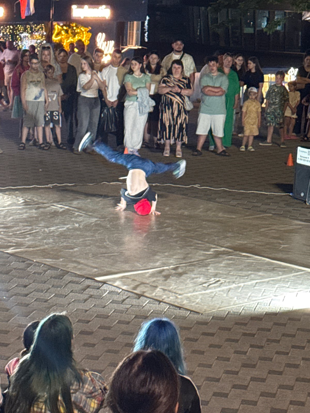 Breakdancers and street musicians perform for a nighttime plaza crowd
