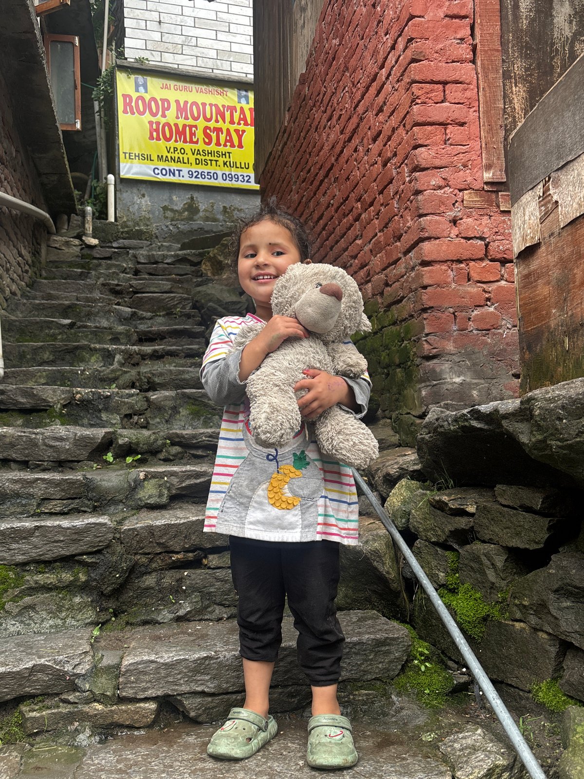 Child with teddy bear on stone steps in Vashisht