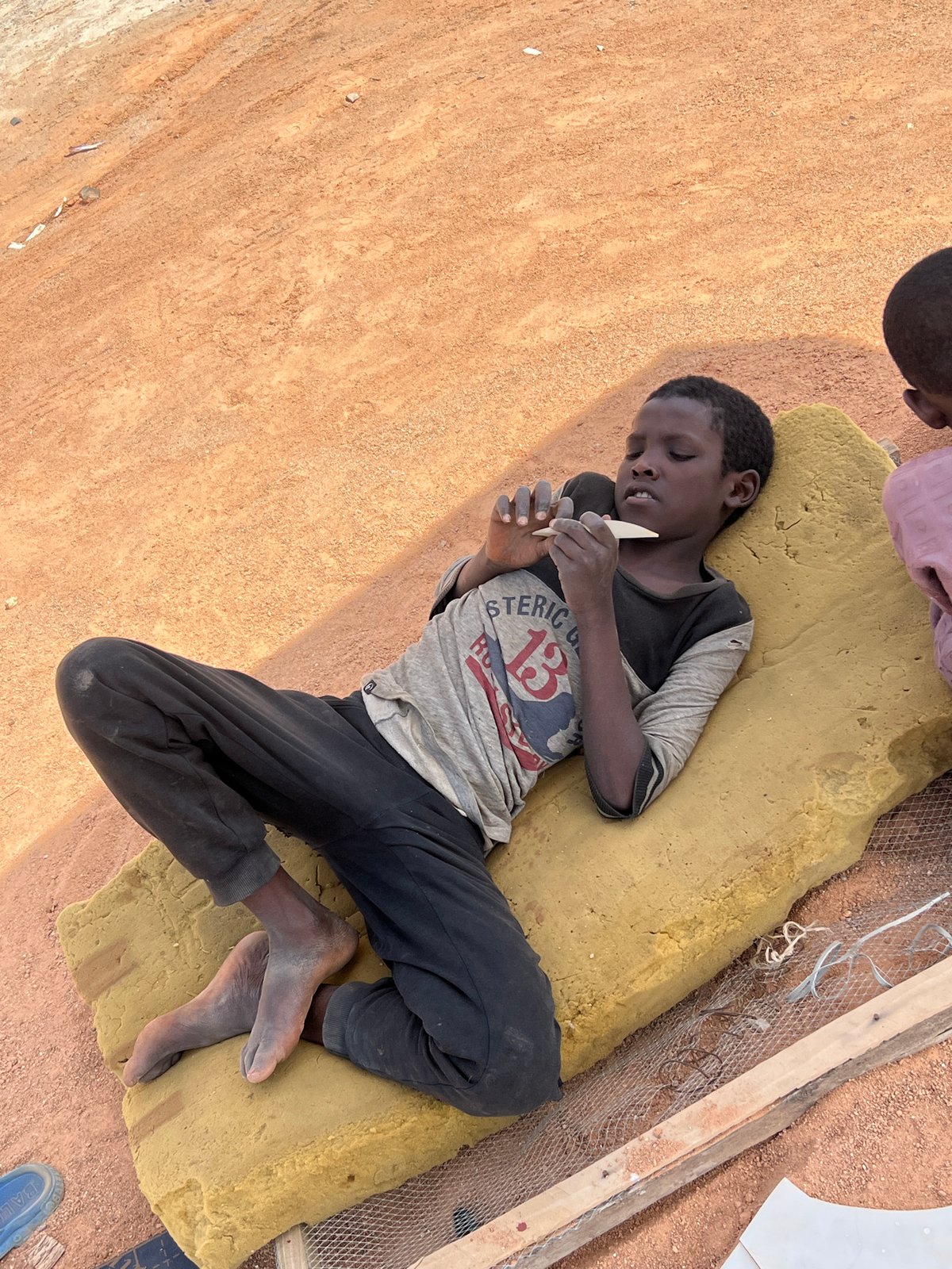 Children rest and play outdoors in Barakin Lerawi