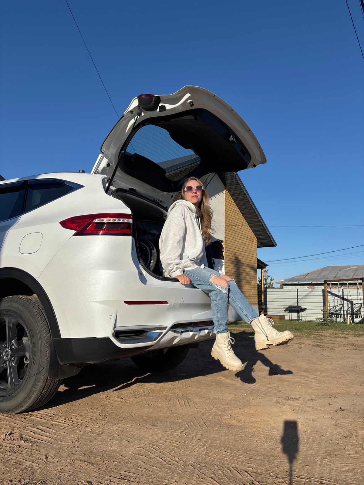 Woman photographed in casual poses around white SUV in Russia