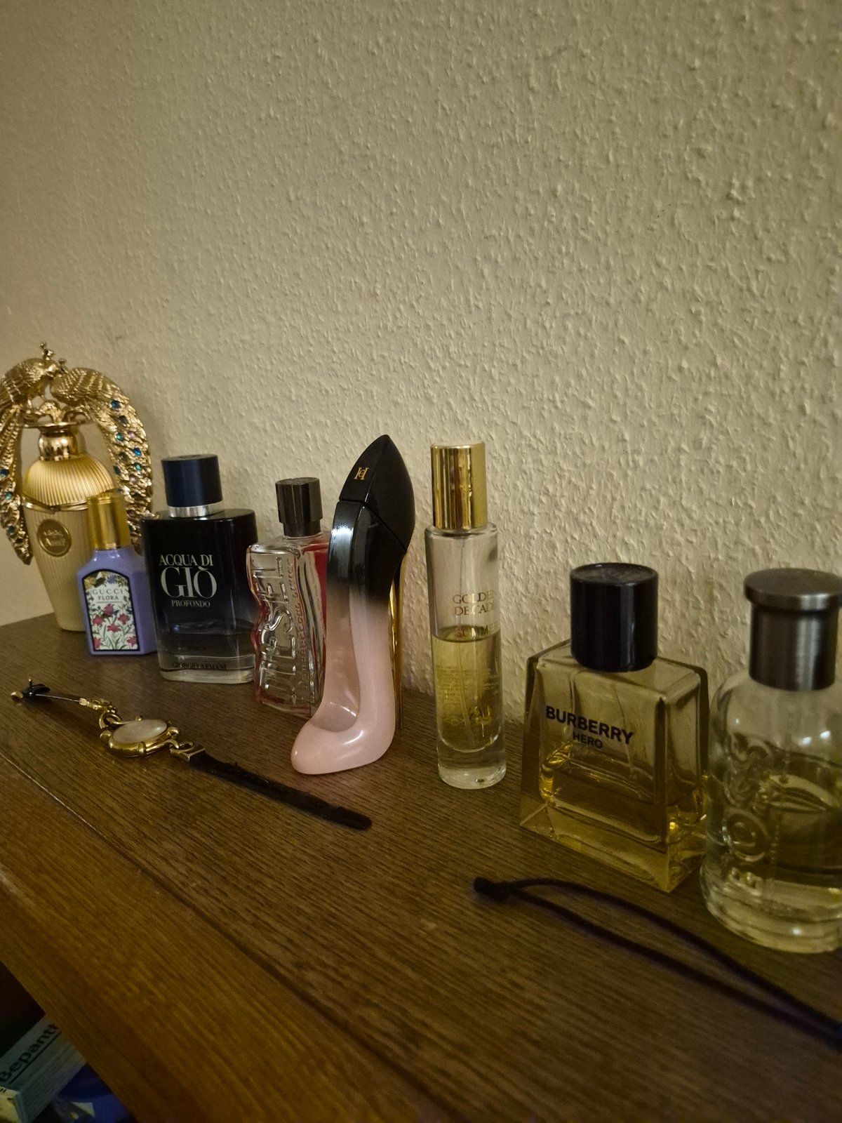 Perfume collection and accessories laid out on a wooden dresser