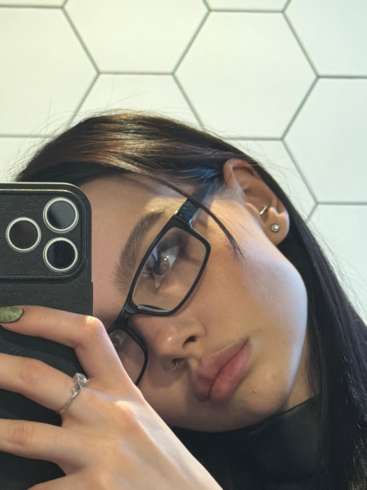 Person takes selfie showing piercings and accessories