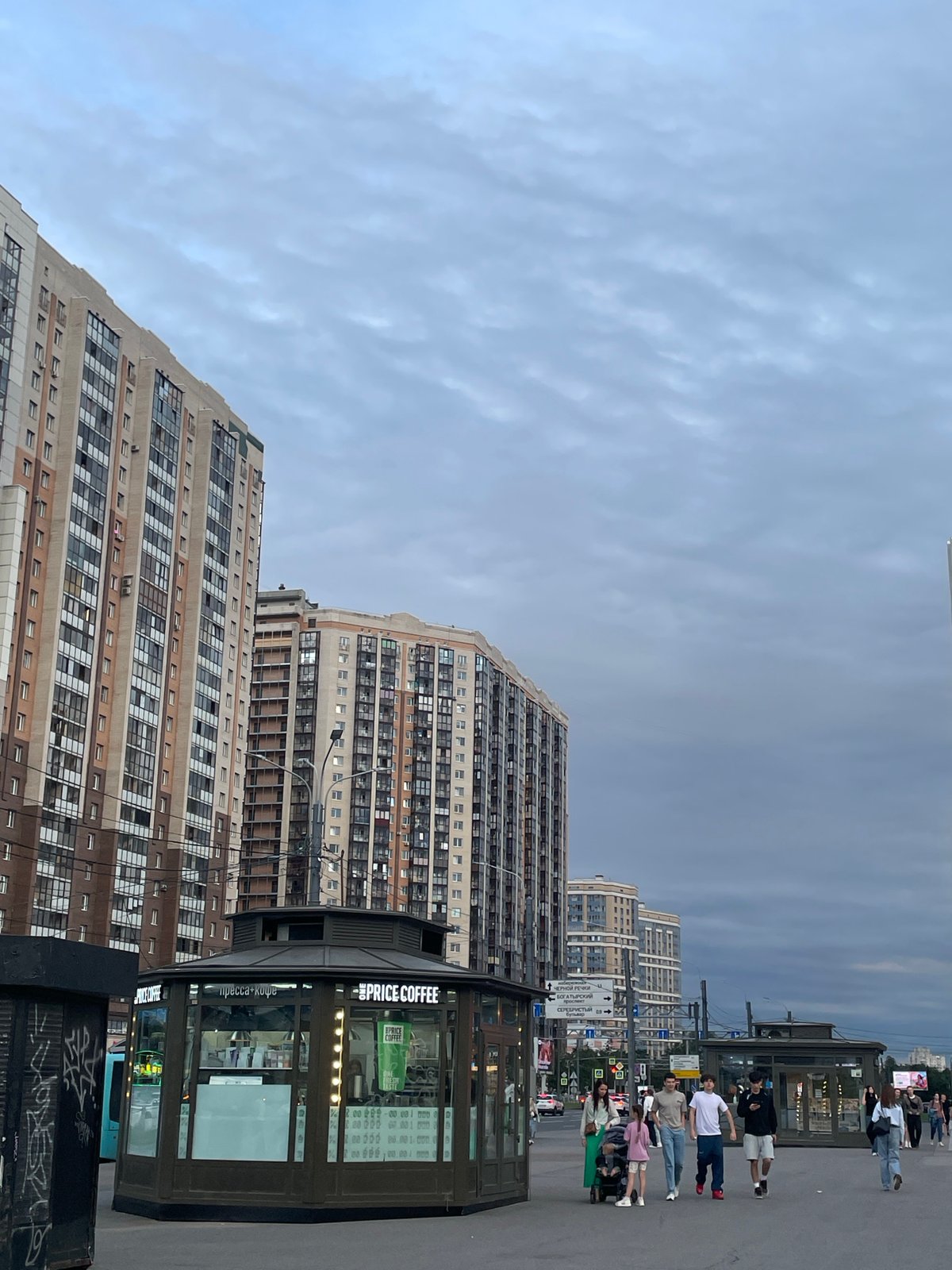 Saint Petersburg street corner: coffee kiosk, curved tower, tram wires