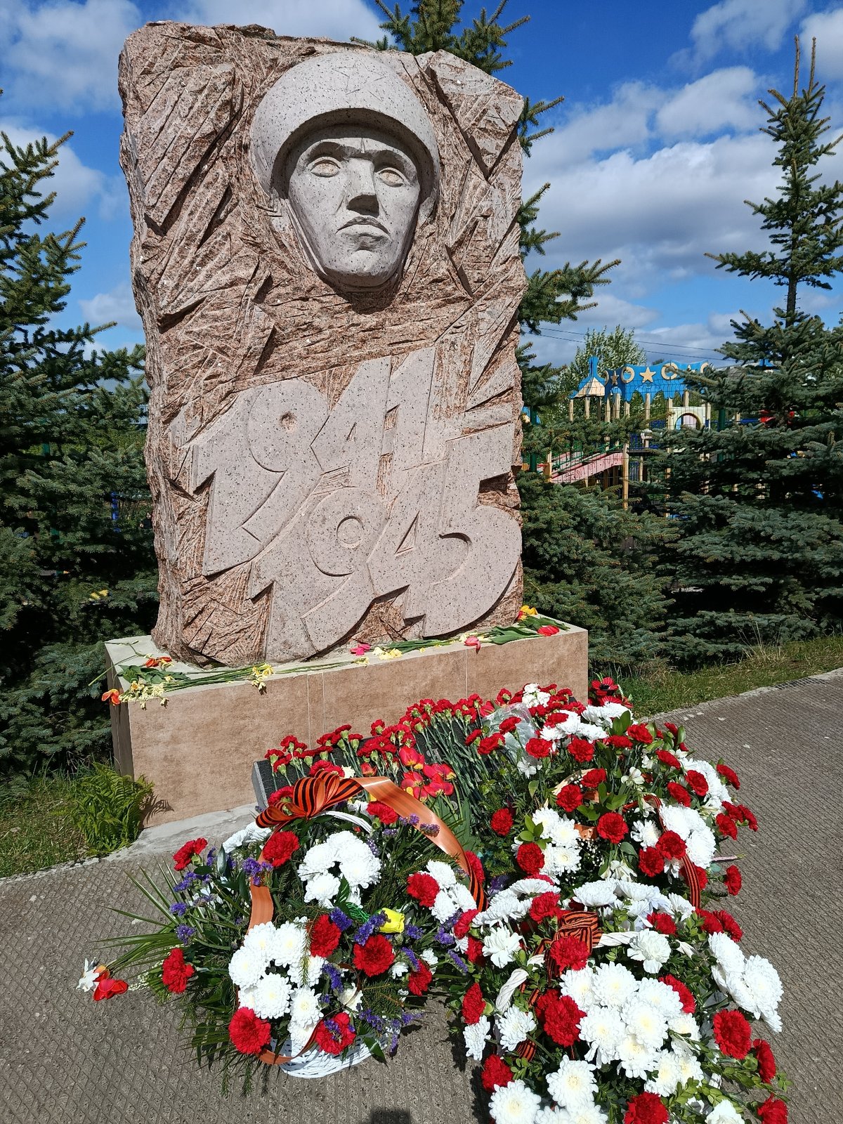 Family visits WWII memorial with flowers in Russian village