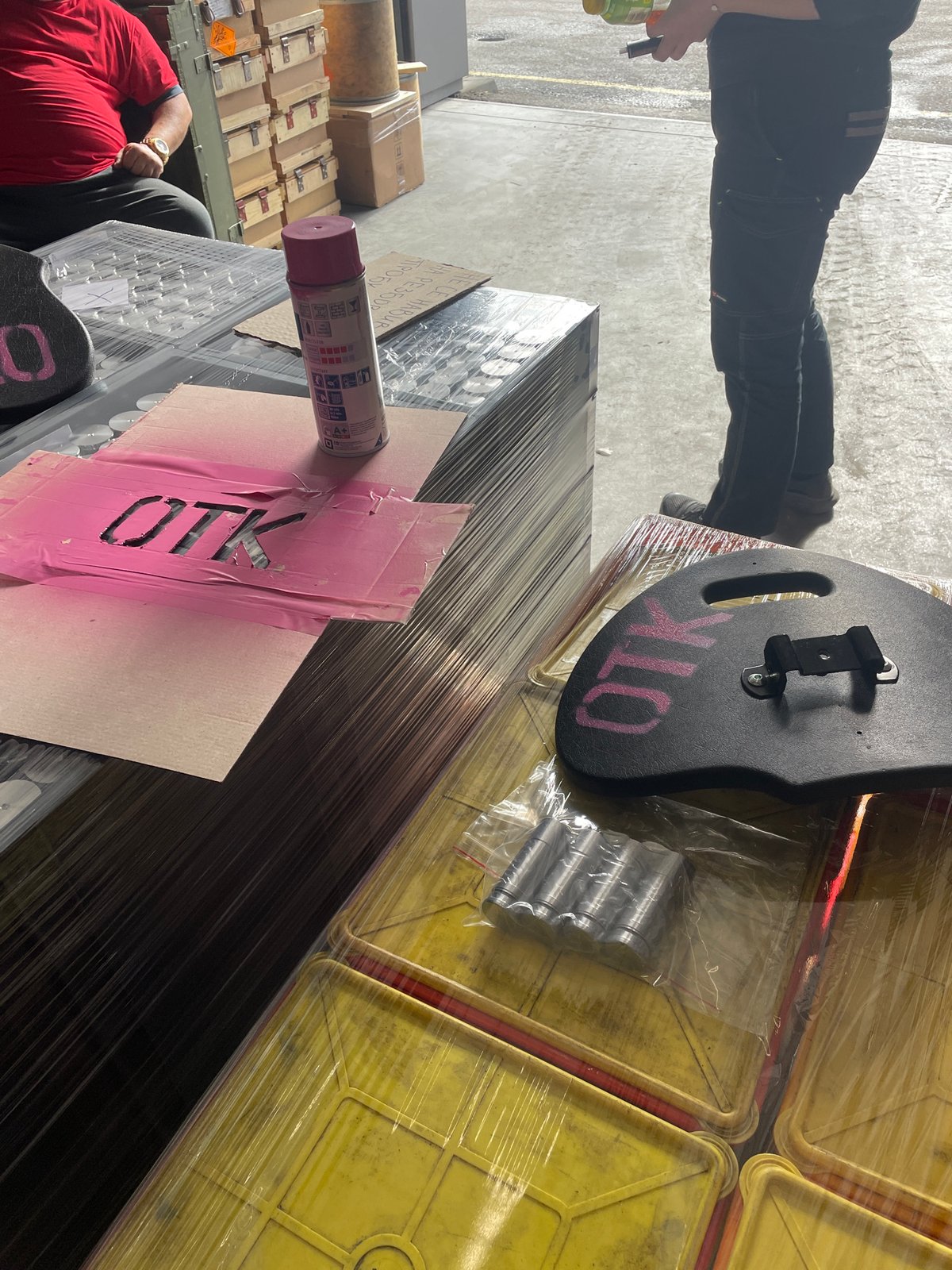 Workers spray paint pink markings on container in Bulgarian warehouse