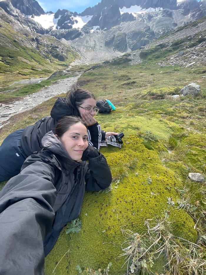 Women rest on mossy mountainside during Ushuaia hiking trip