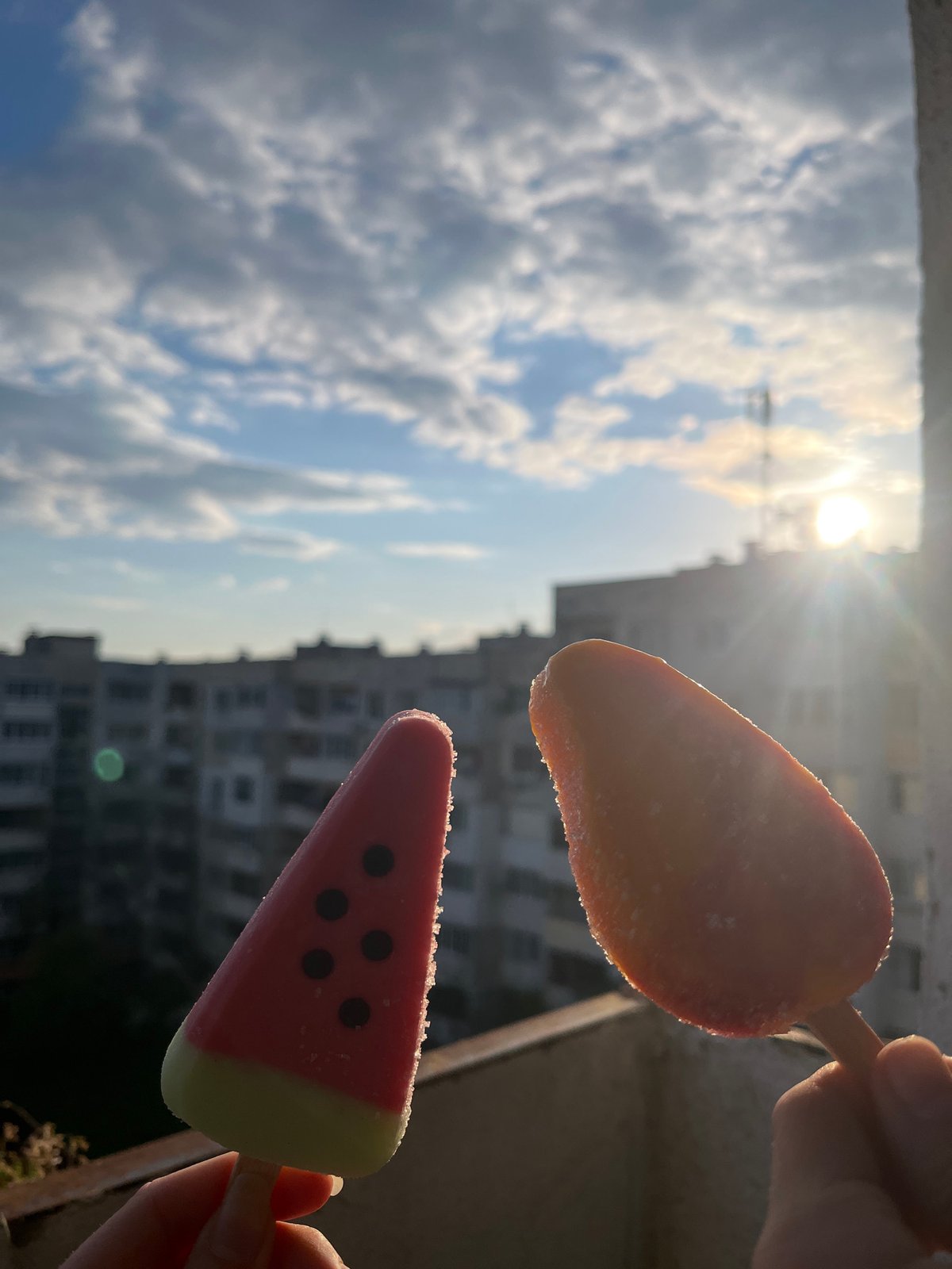 Person enjoys watermelon popsicles under sunny Sofia sky