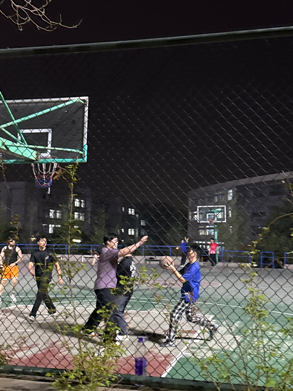 Nighttime basketball game observed at Zhongtun court