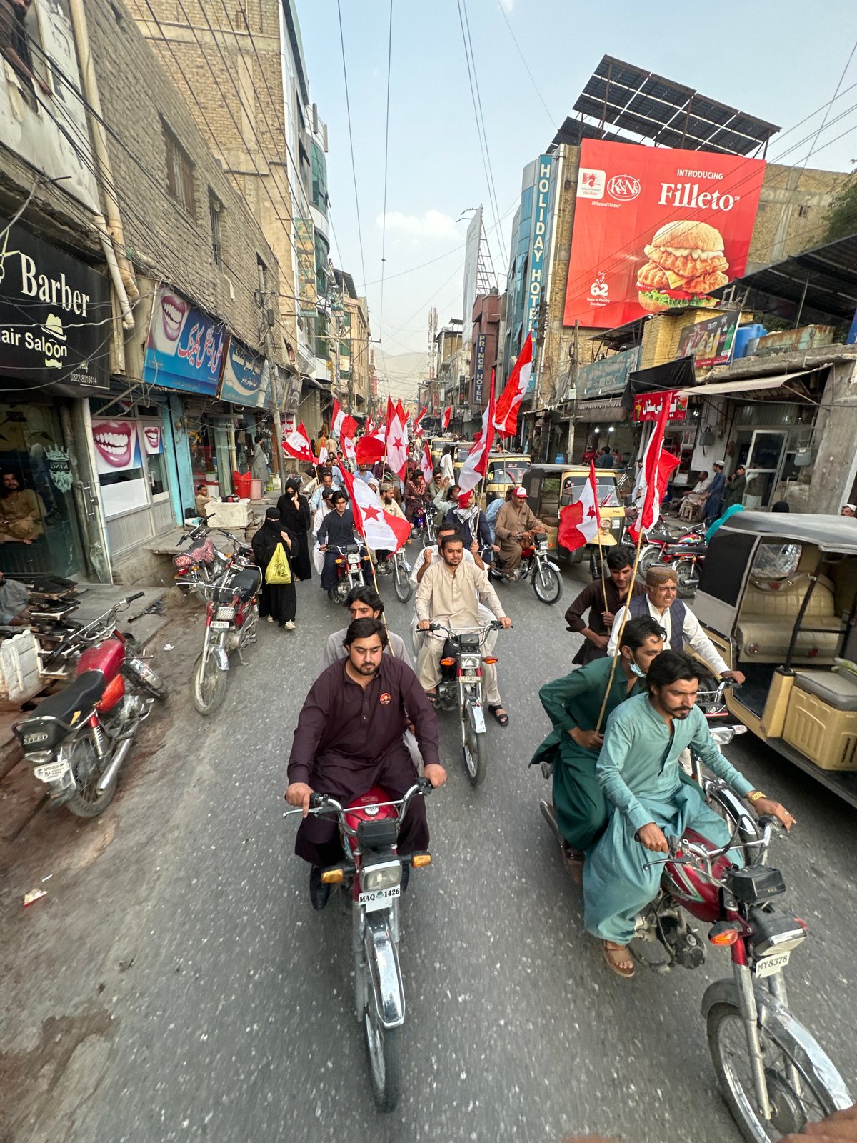 Flag-bearing procession rolls through Quetta's busy commercial streets