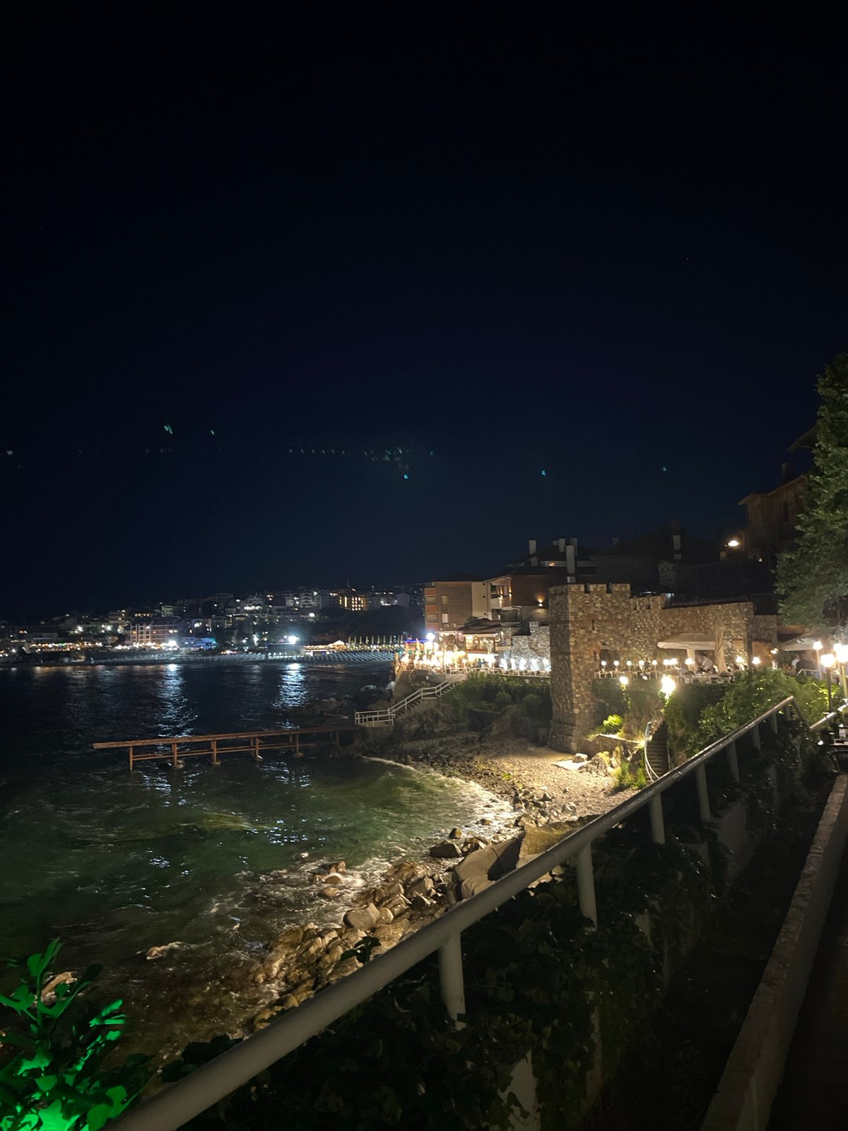 Nighttime coastal town lights reflect off calm water