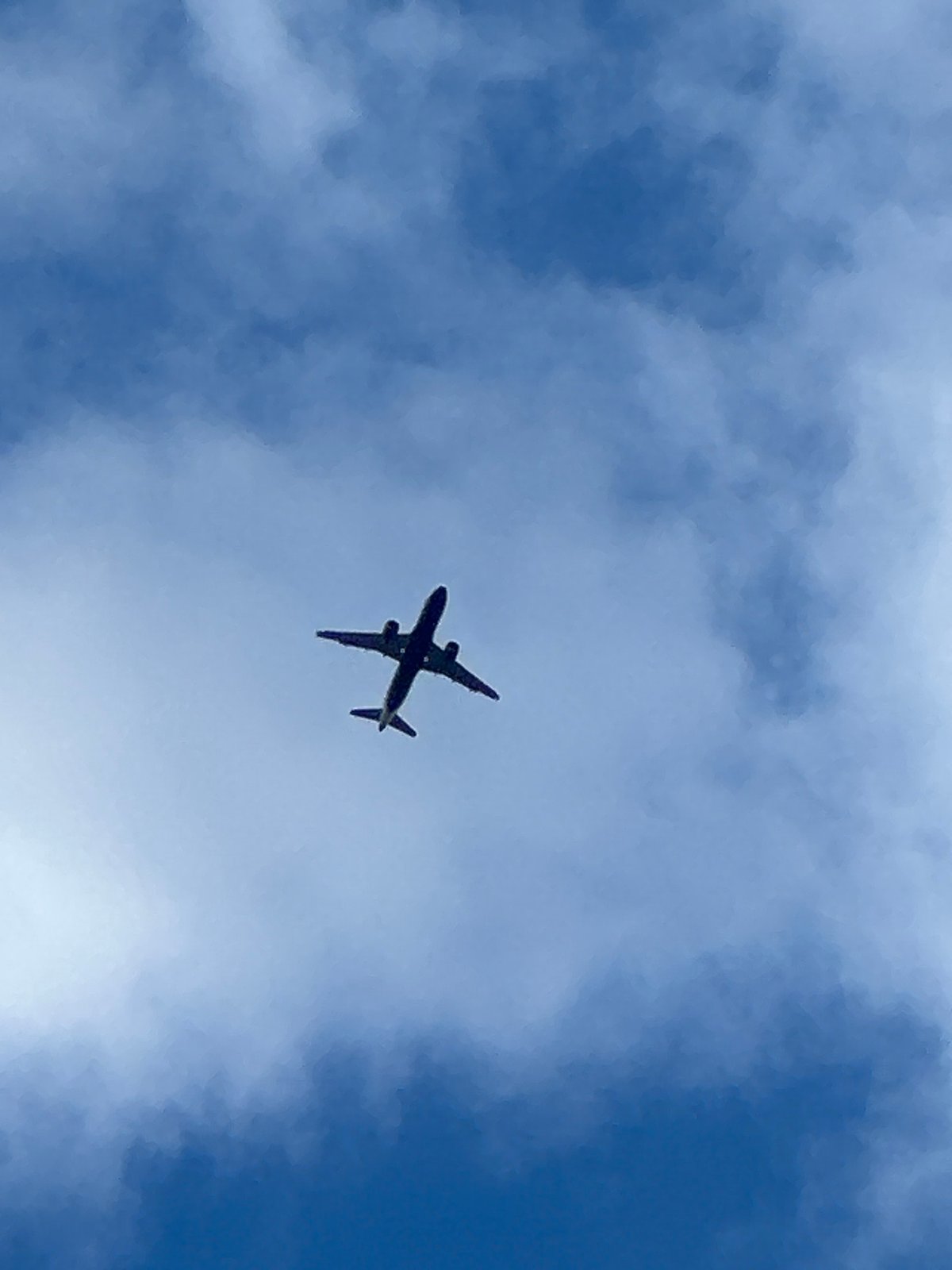 Aircraft passes overhead through patchy skies over southeast London