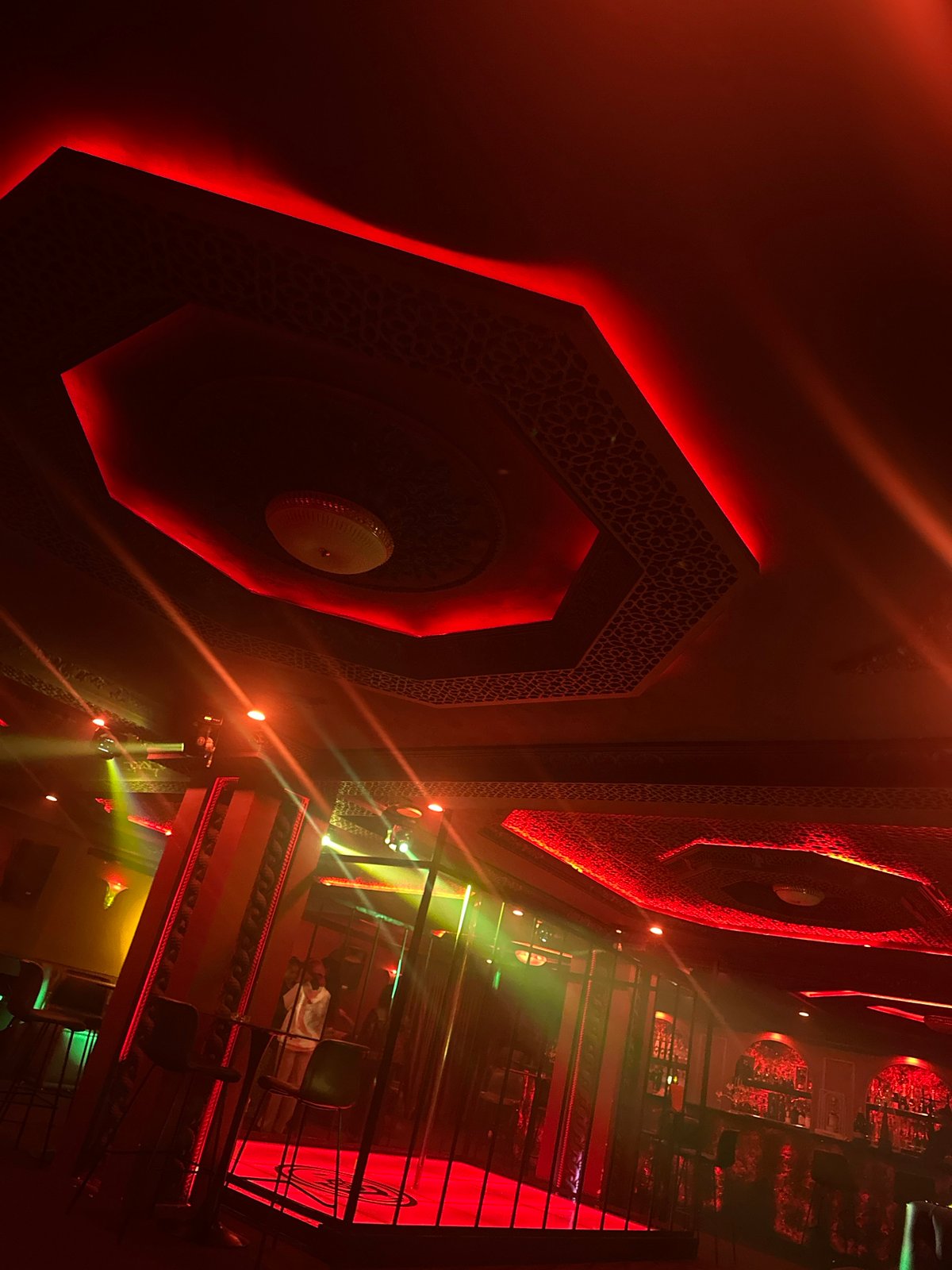 Inside a red-lit Abuja nightclub with historic portrait decor