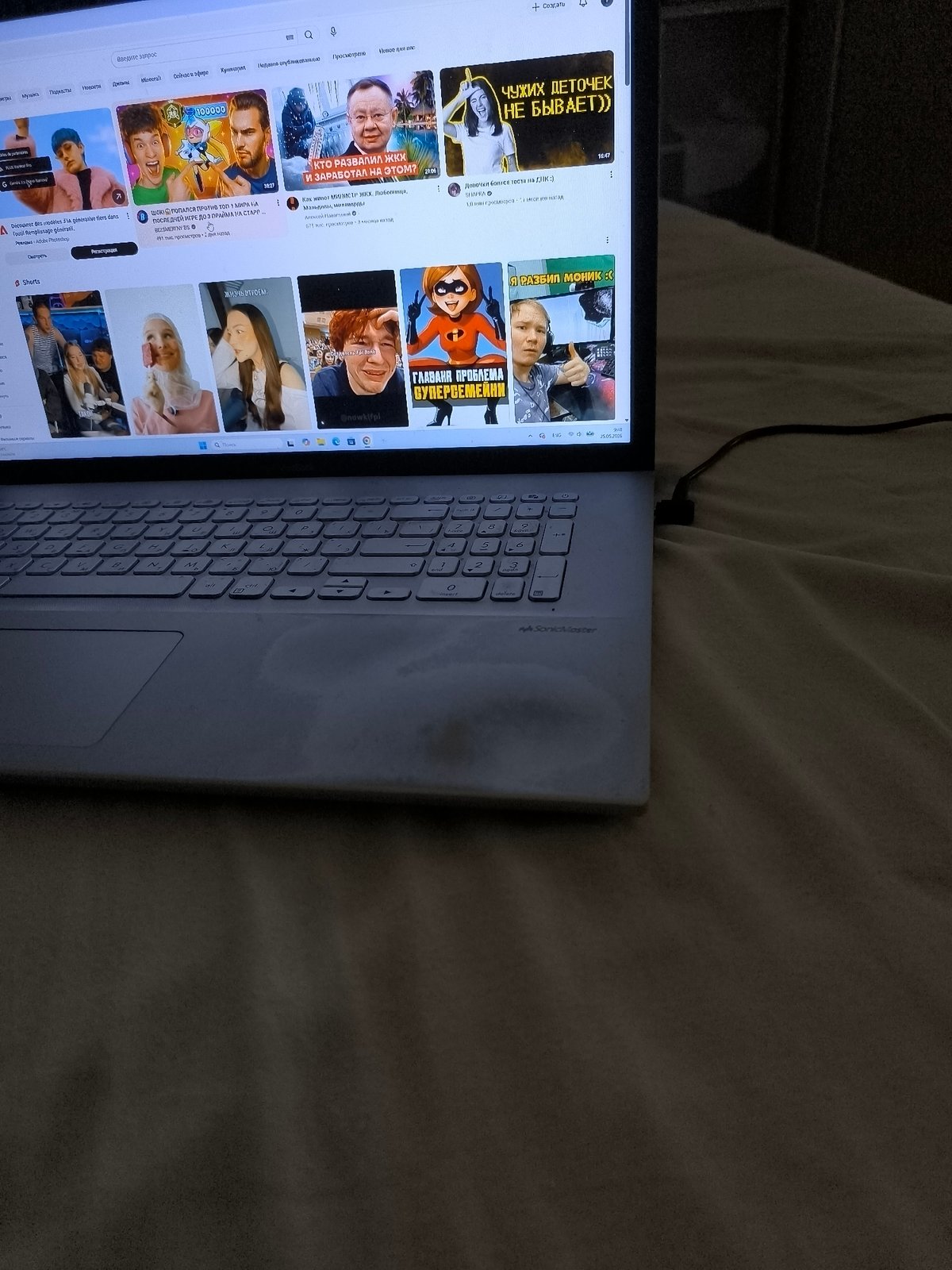 Person browsing Russian YouTube on laptop in French bedroom