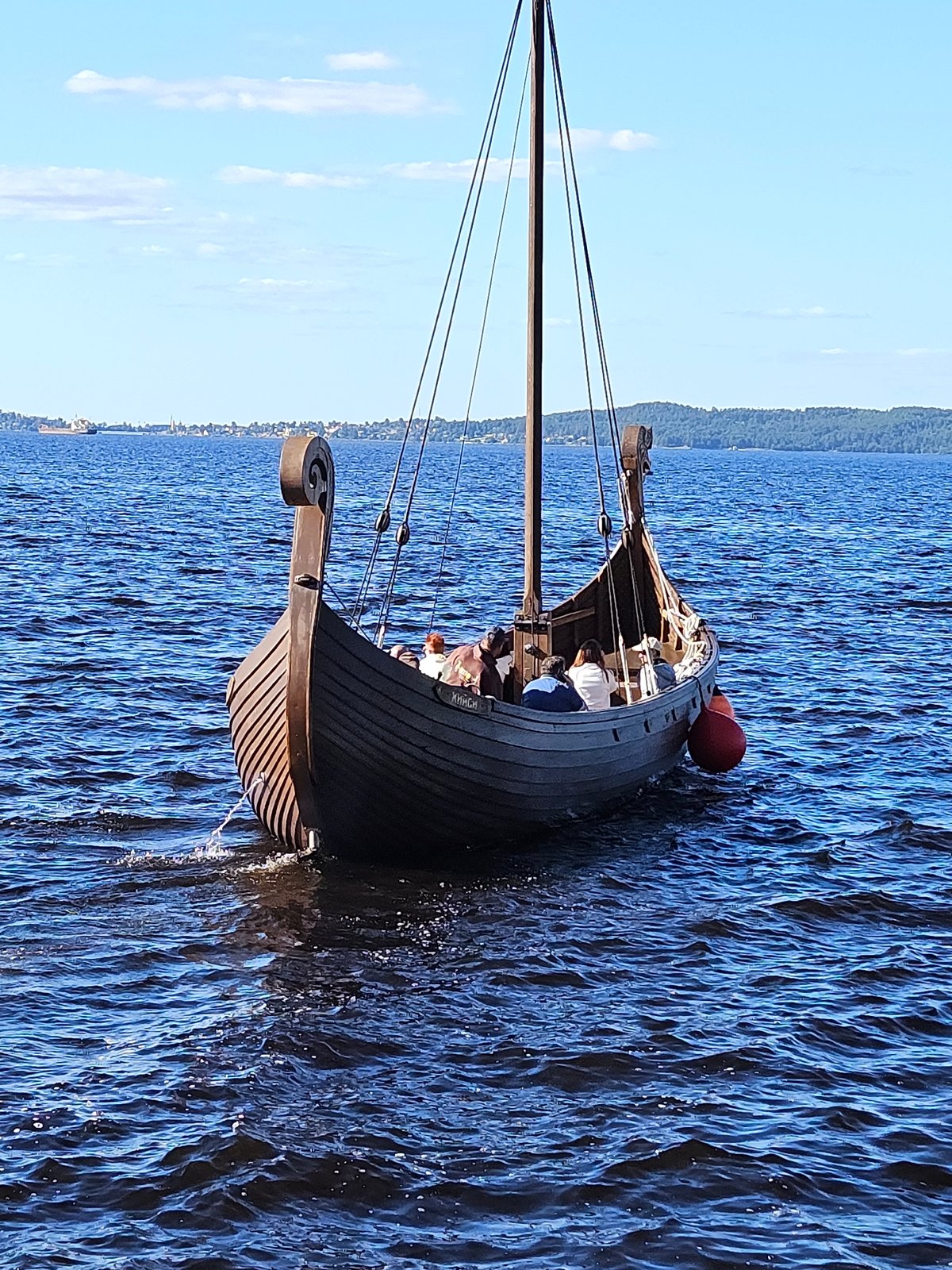 Viking ships, hydrofoils, and sculptures along a calm blue waterfront