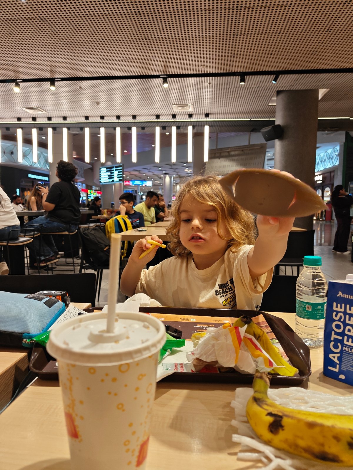 Child holds cardboard lid at Mumbai food court