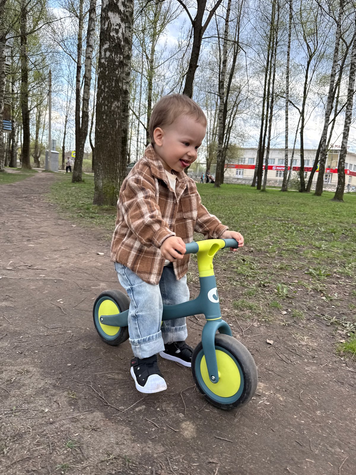 Toddler bikes while woman relaxes in Rusanovo park