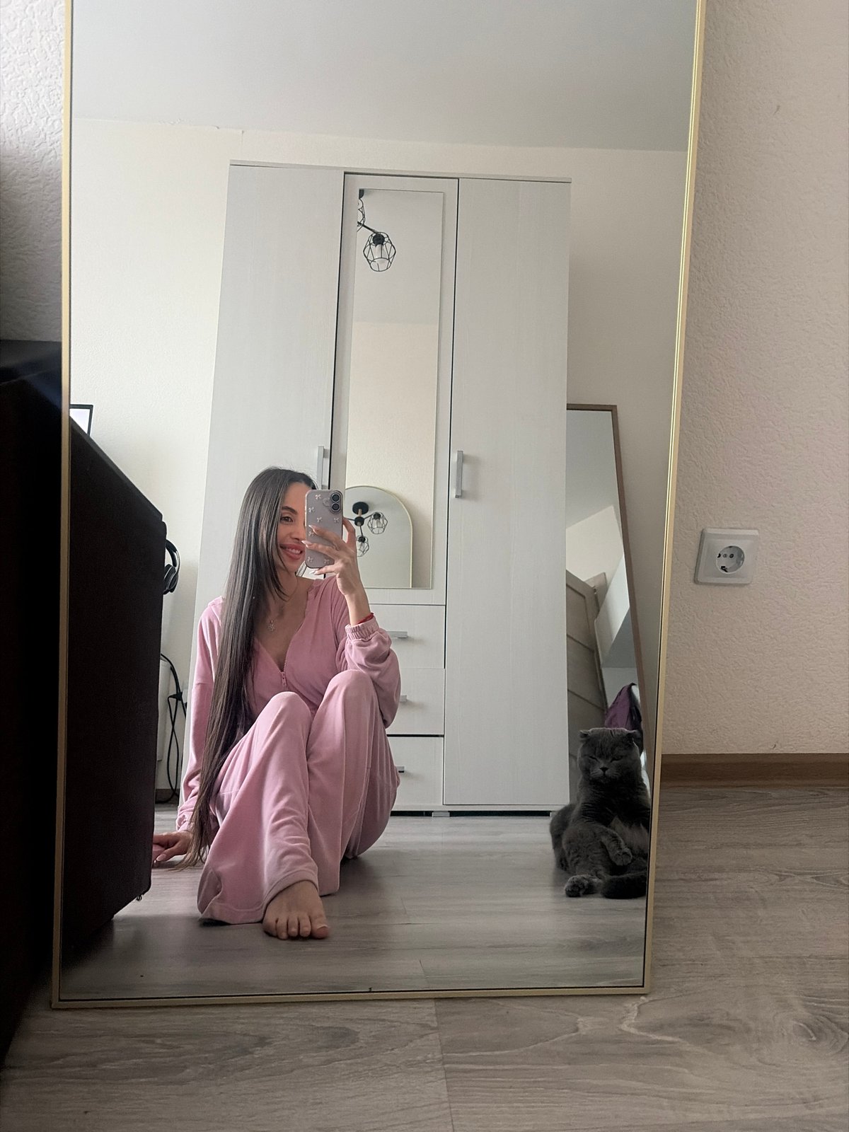 Woman takes playful selfies in pink tracksuit, Saint Petersburg apartment
