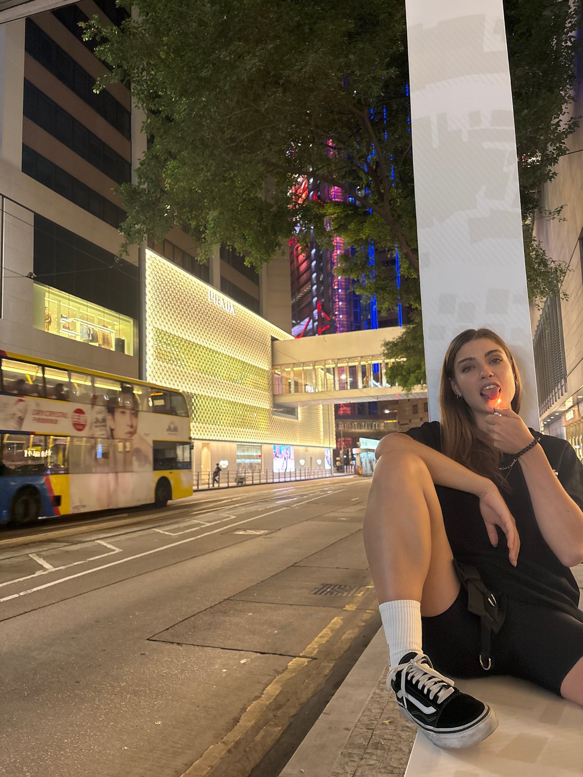 Woman sits on ledge holding lighter in Hong Kong