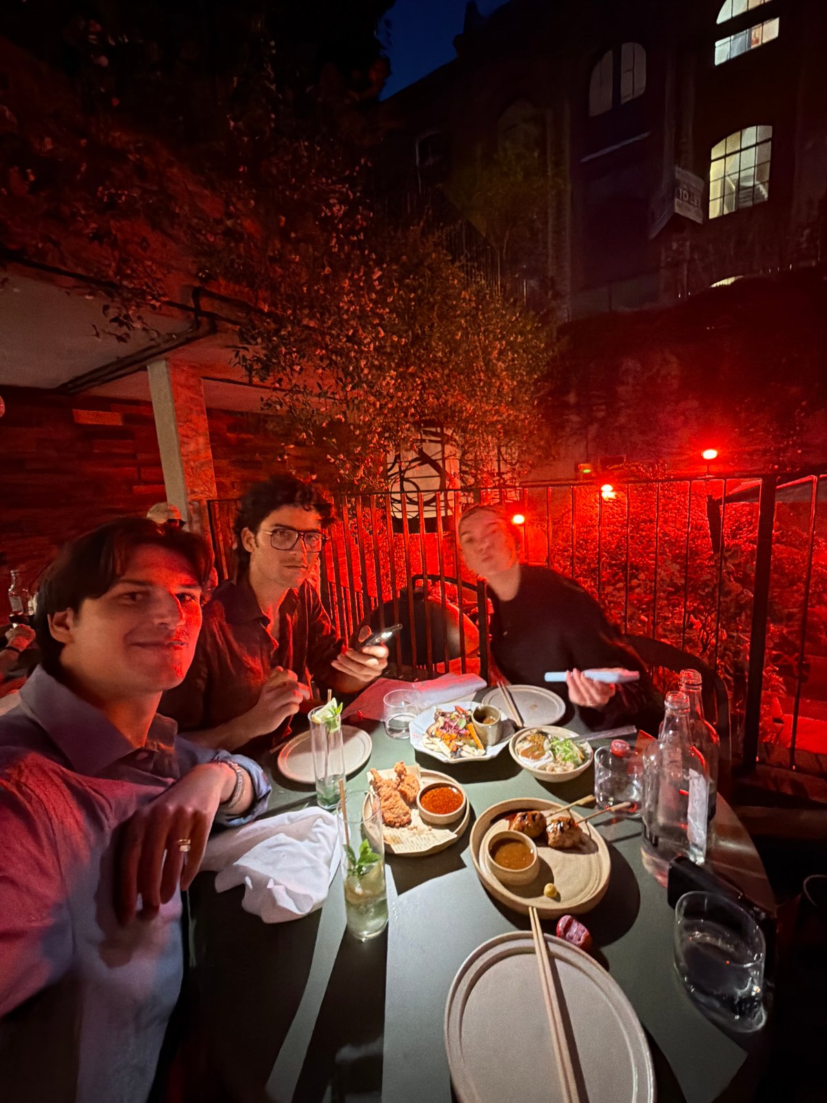 Late-night outdoor dining in London, red-lit rooftop setting