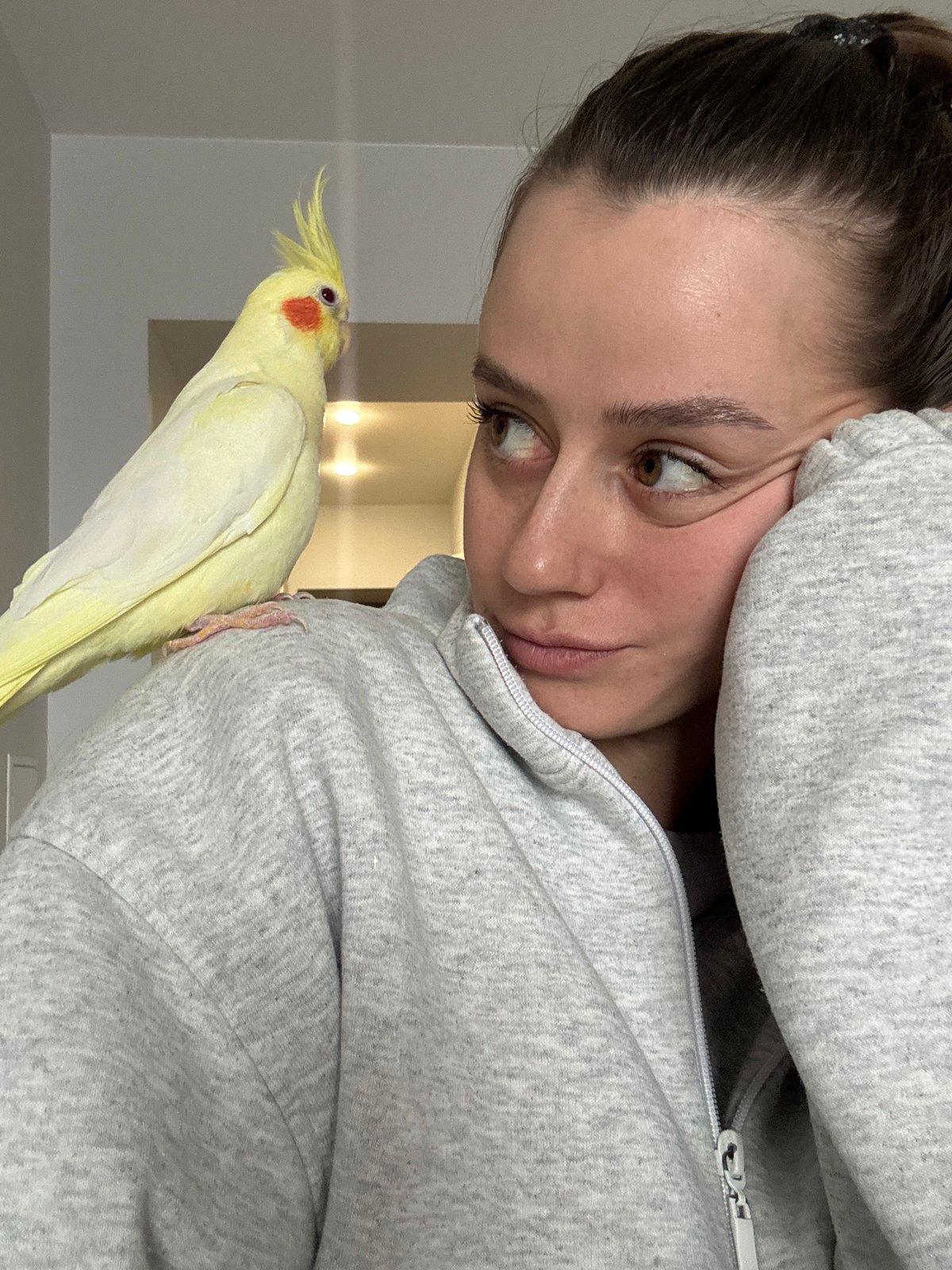 Woman bonds with pet cockatiel during morning in Krasnoyarsk