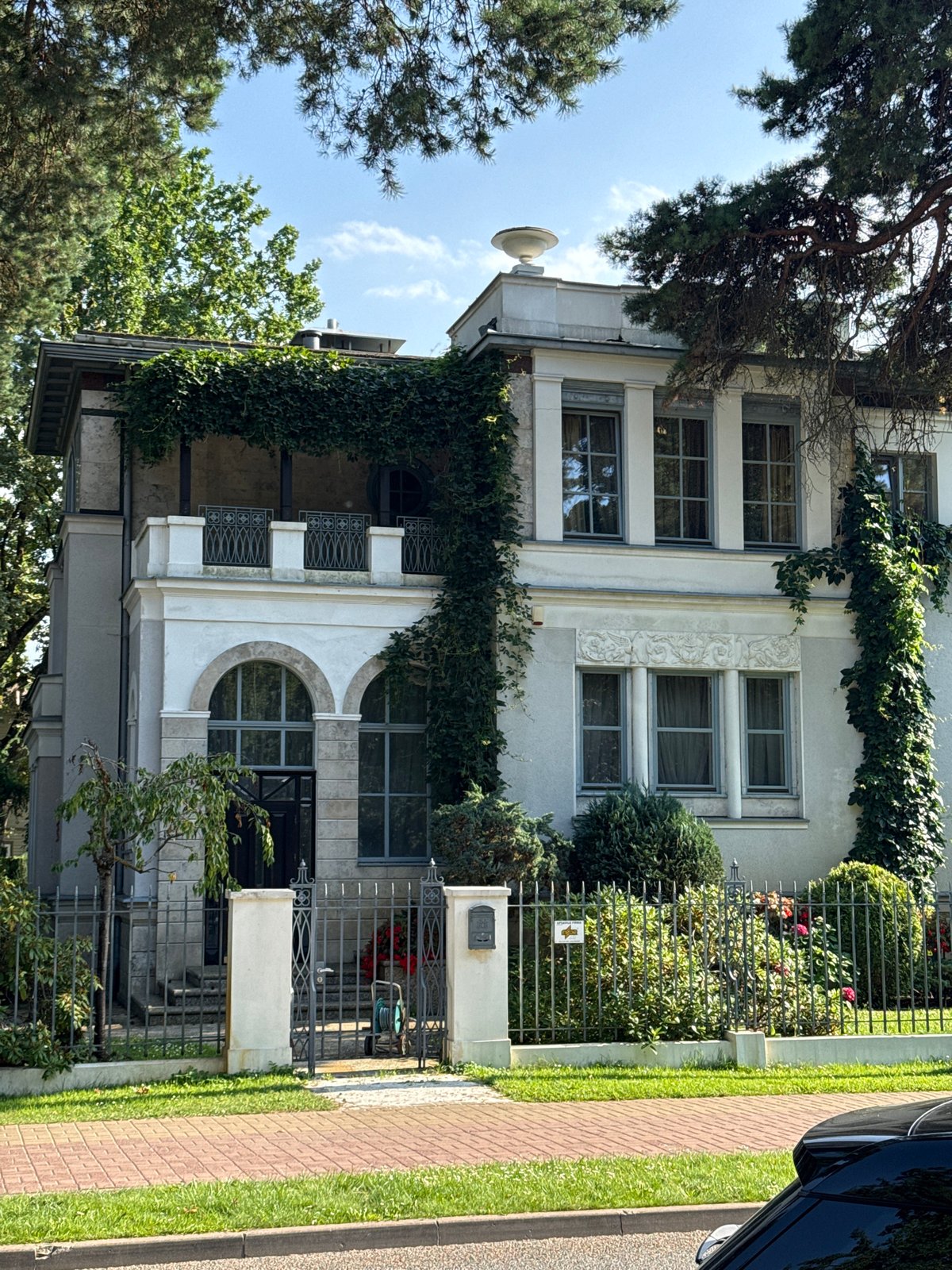 Ivy-covered white house behind iron gate in Jūrmala