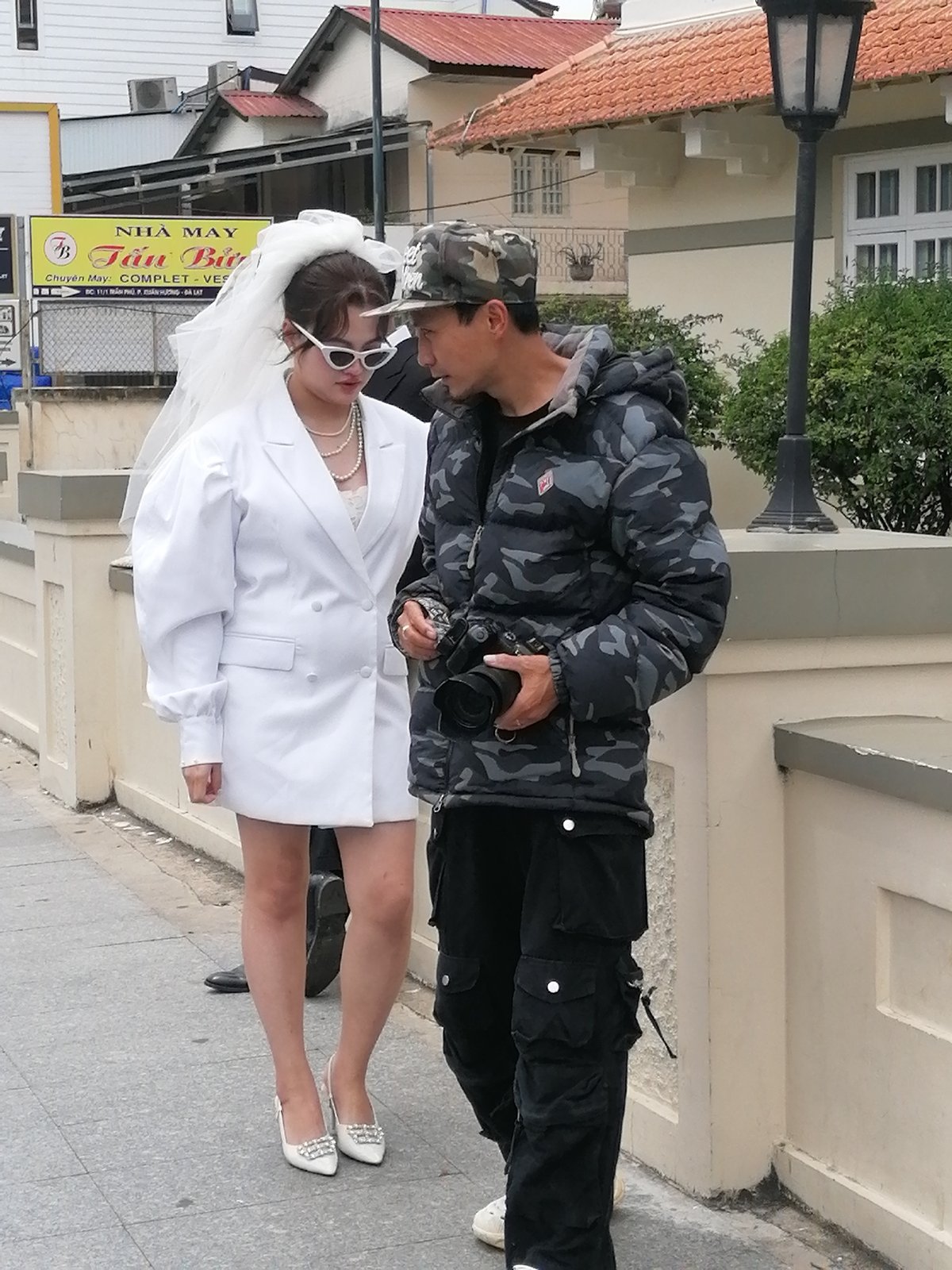 Bride and photographer ready up on a sidewalk for a shoot