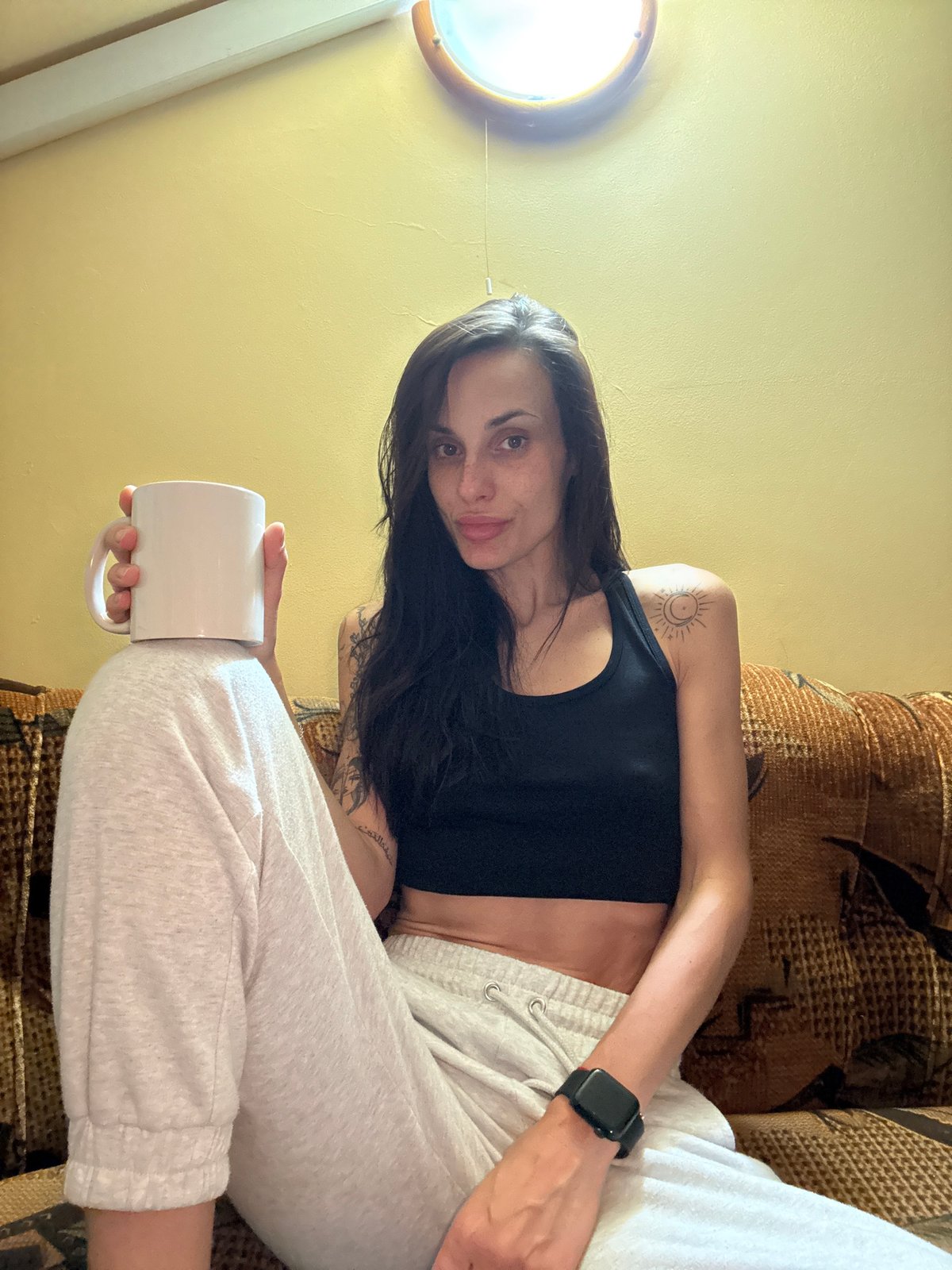 Woman relaxes on sofa with mug in Pleven
