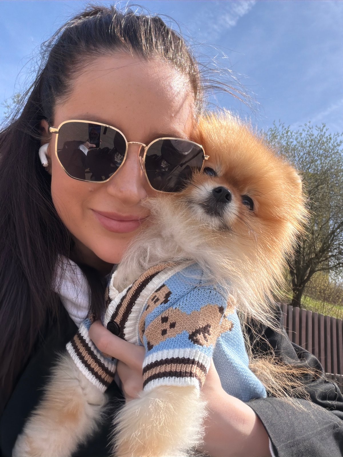 Woman walks Pomeranian through Khimki neighborhoods on sunny morning