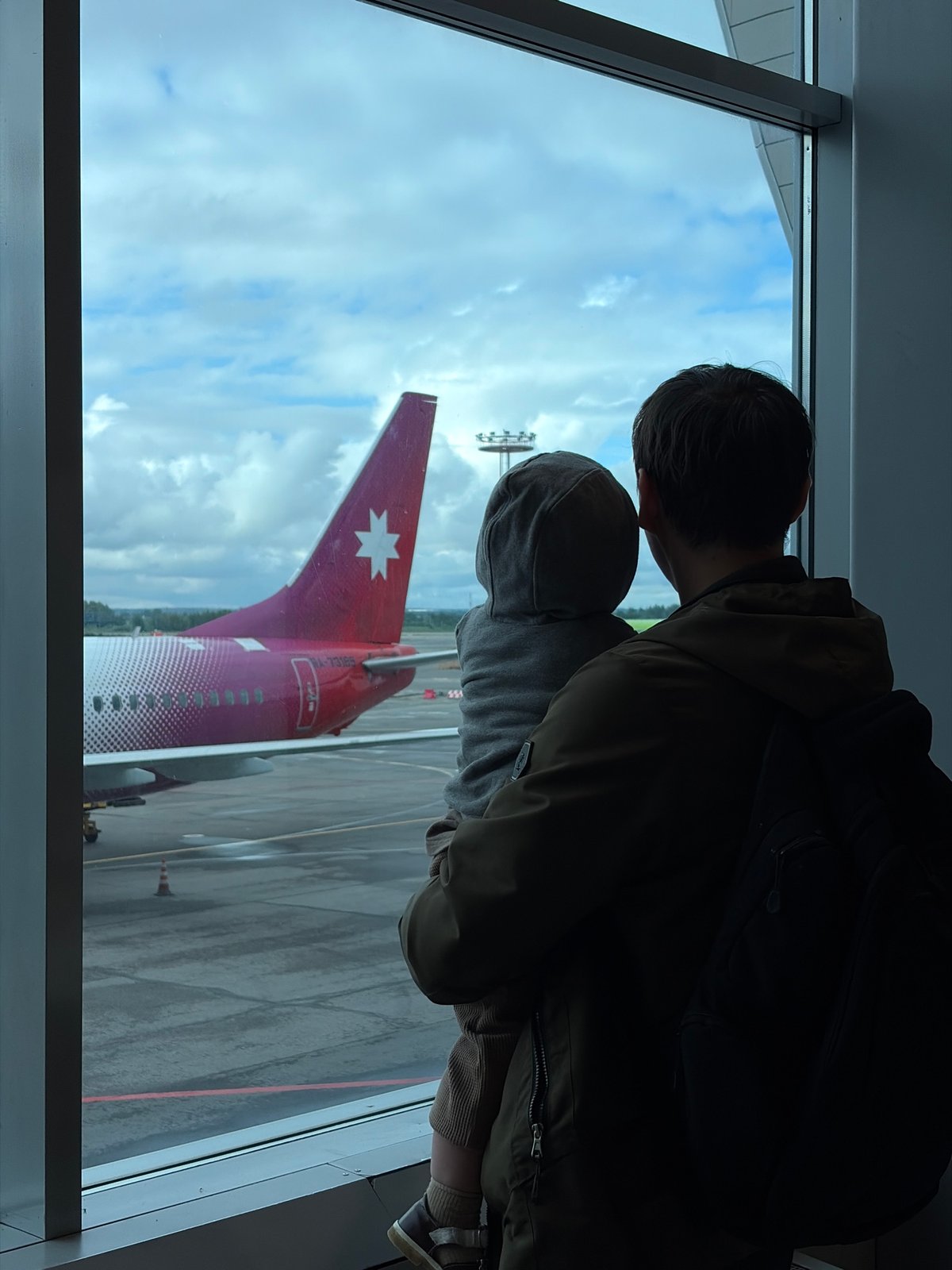 Parent and child watch distinctive pink aircraft at Moscow airport