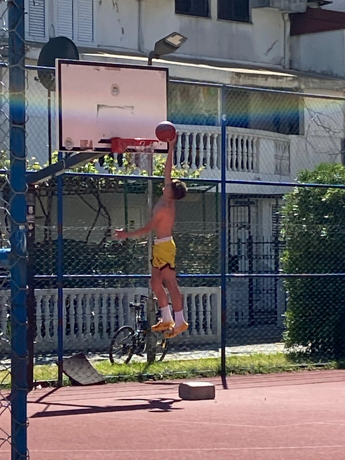 Young player shoots hoops in sunny Budva courtyard