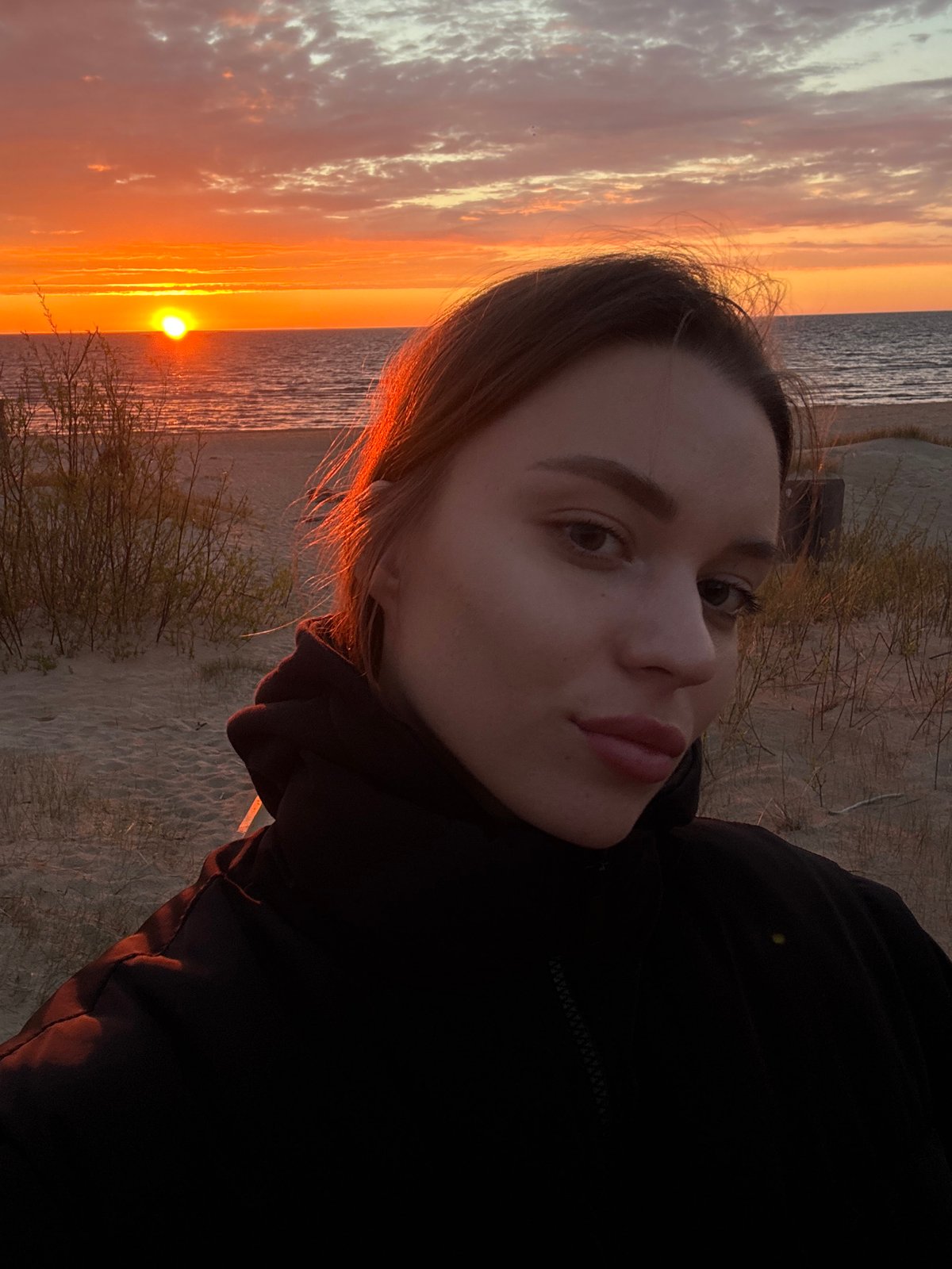 Woman photographed against sunset seascape in Ādaži, Latvia