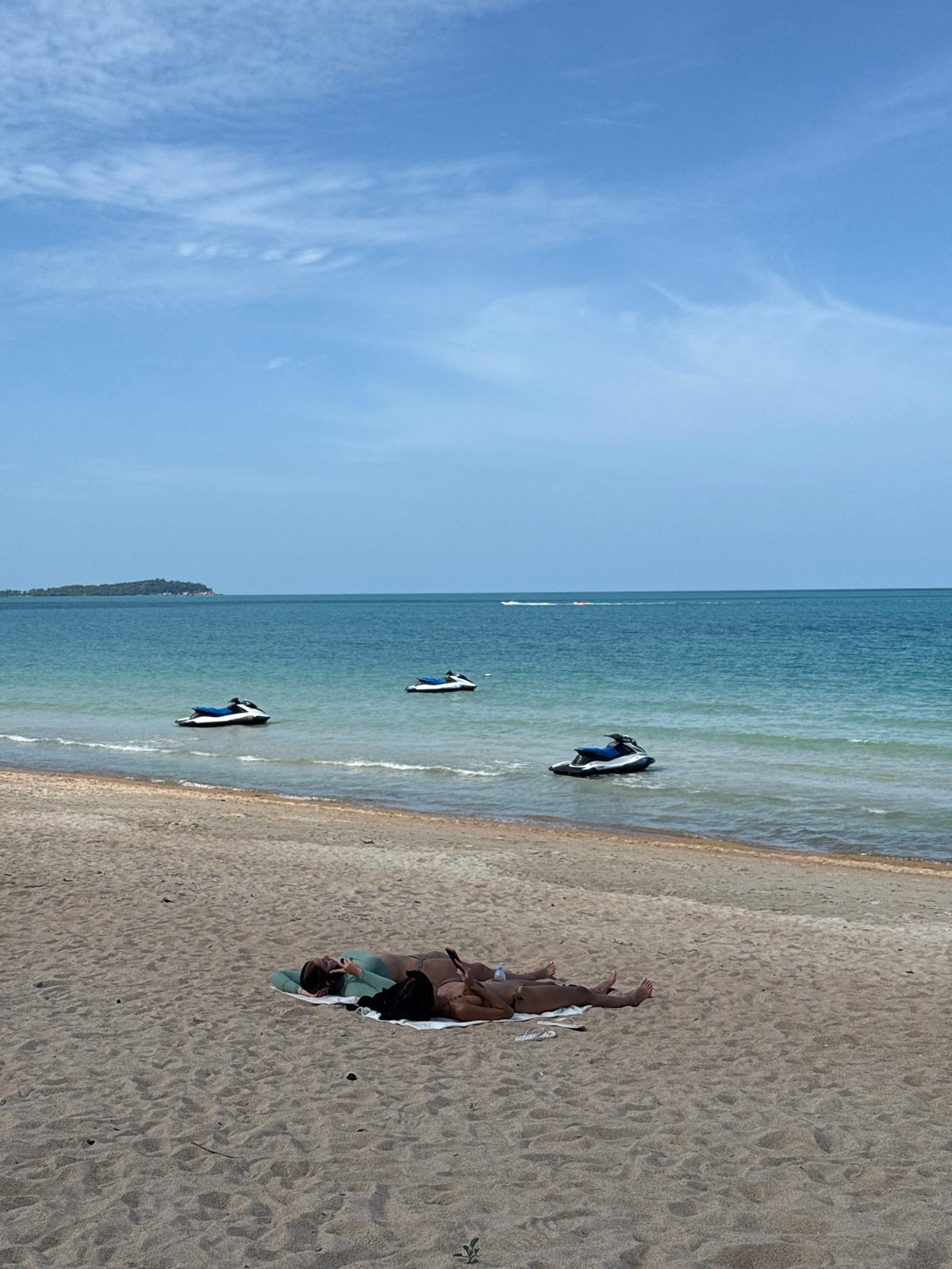 Busy beach morning on Ko Samui, jet skis and sunbathers in view.