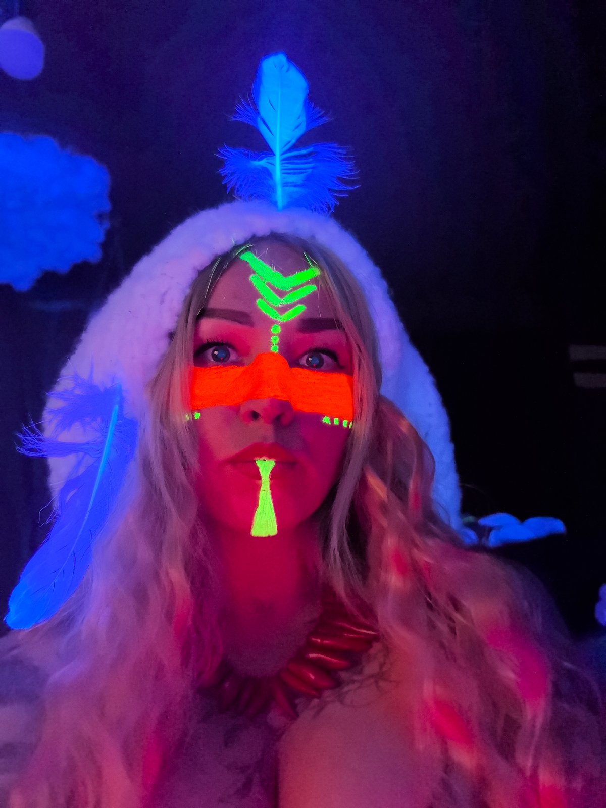 Woman photographed with glowing face paint under UV light