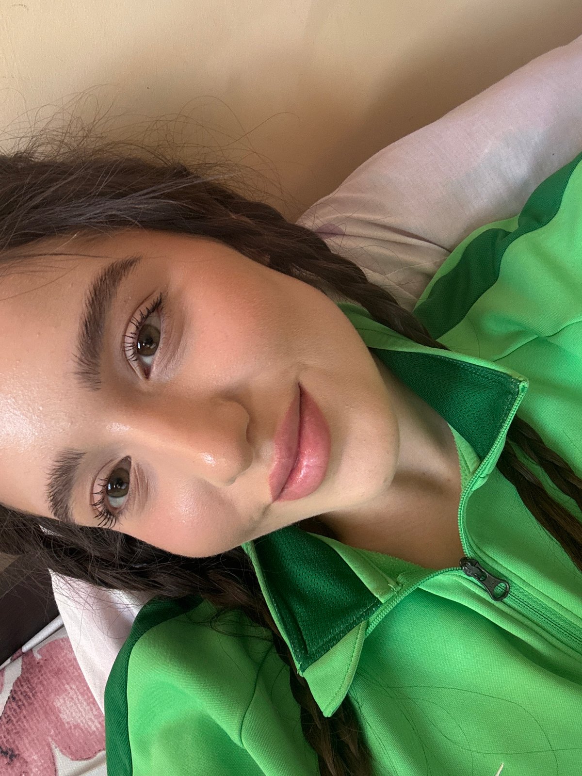Woman in green tracksuit rests on patterned surface