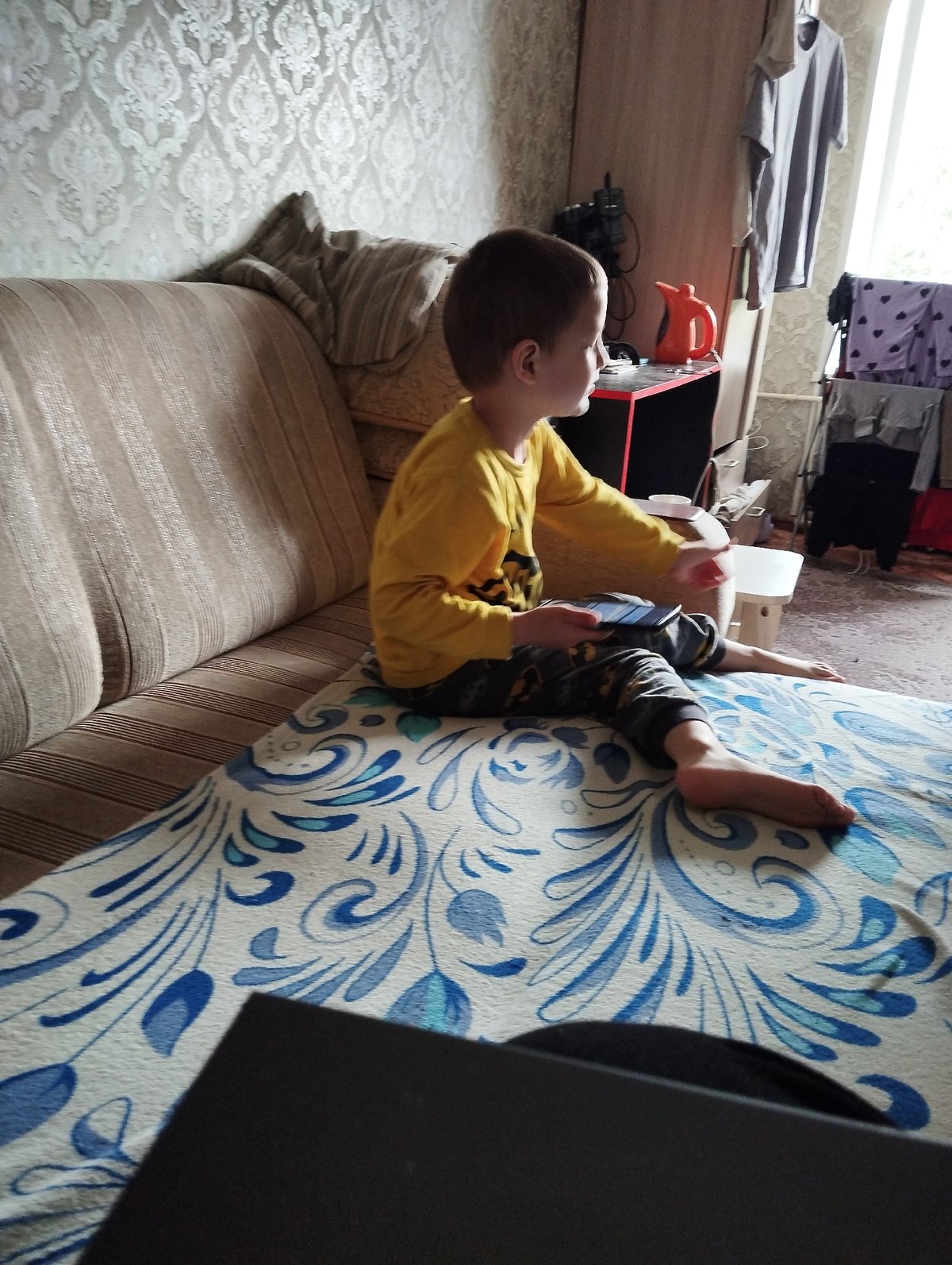 Handheld gaming on a striped sofa in Kingisepp