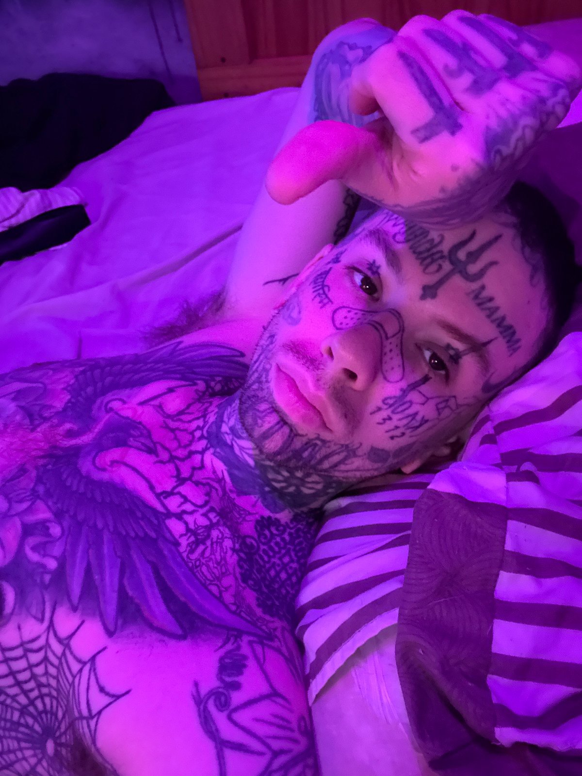 Heavily tattooed man resting on bed in Buenos Aires