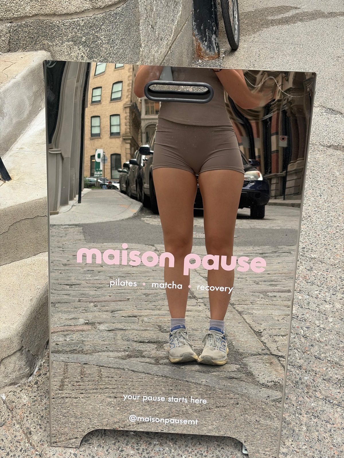 Woman's reflection captured in street mirror sign in Montreal