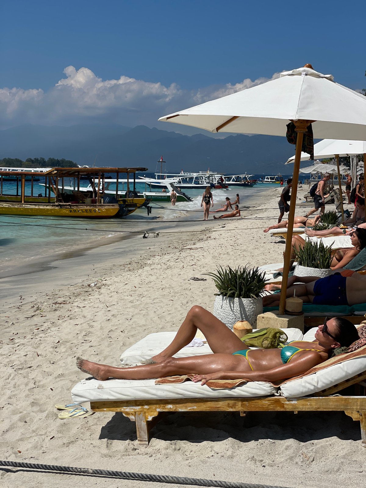 Lazy beach morning with boats, swimmers, and shoreside lounging