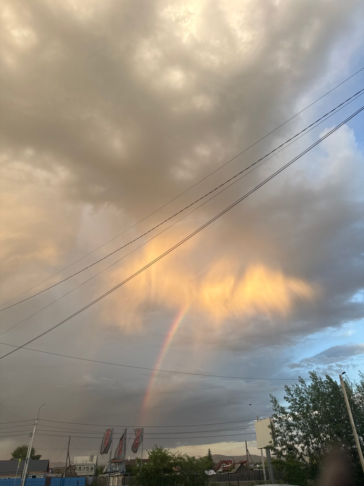 Rainbow appears over urban area amid dramatic clouds