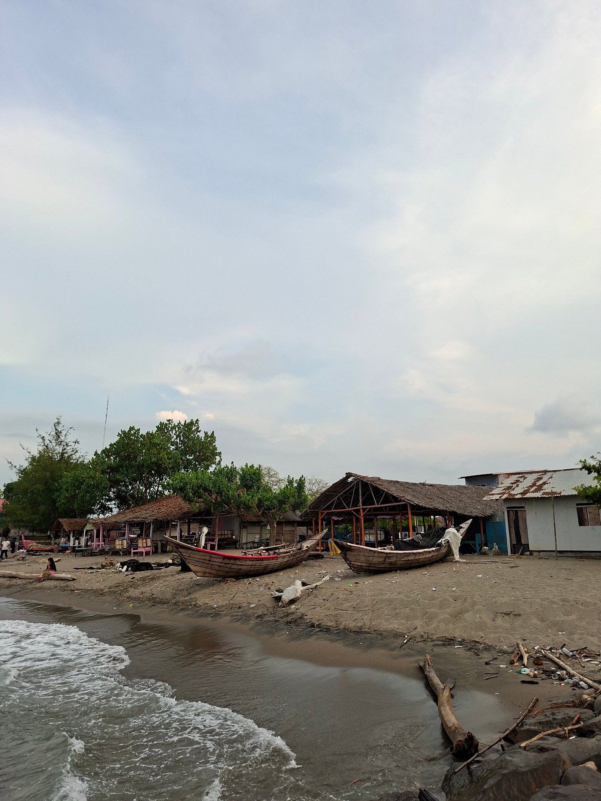 Beachgoers enjoy calm waters in Lhokseumawe under cloudy skies