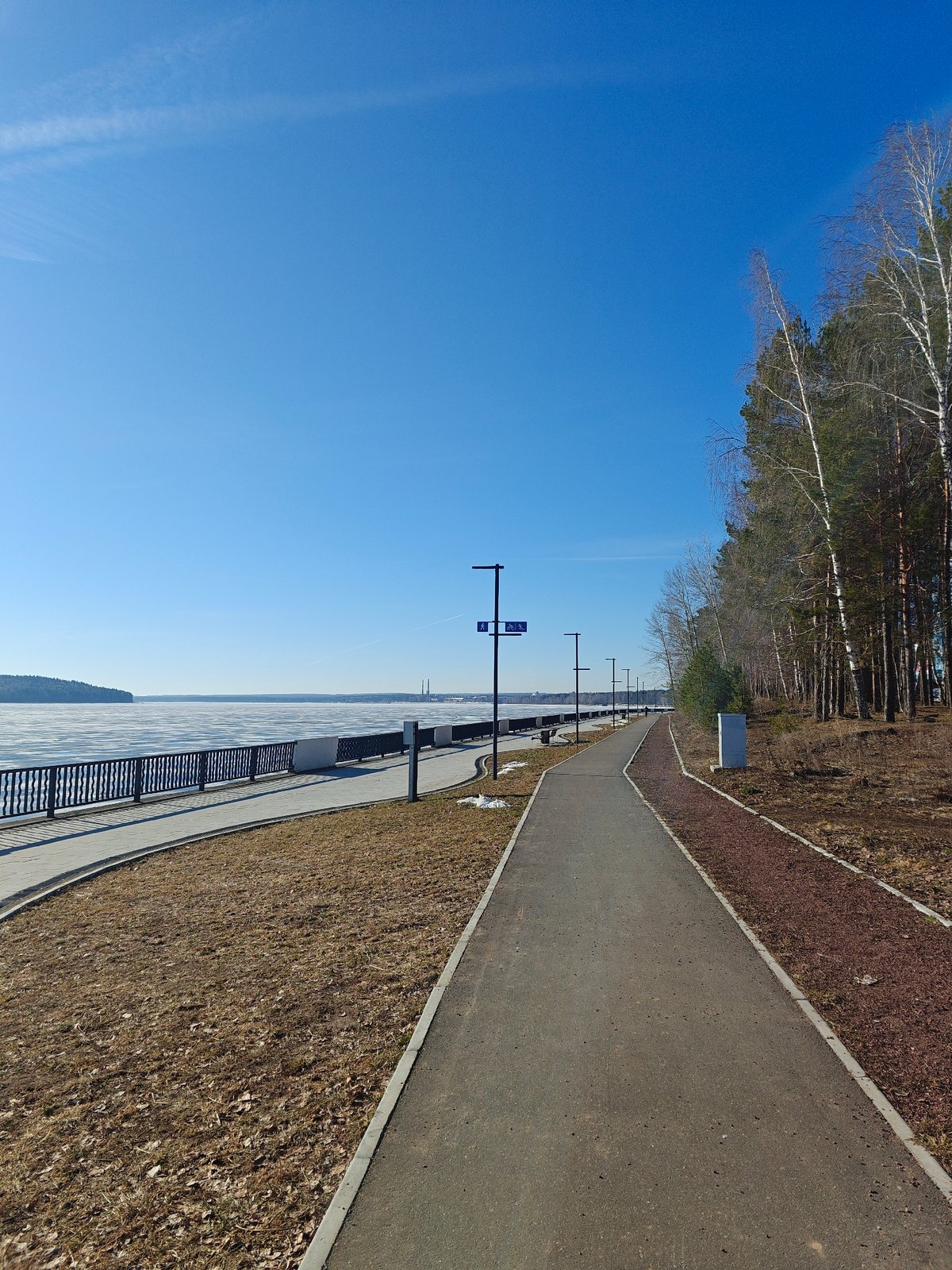 Early morning cyclist rides frozen reservoir path in Chaikovsky